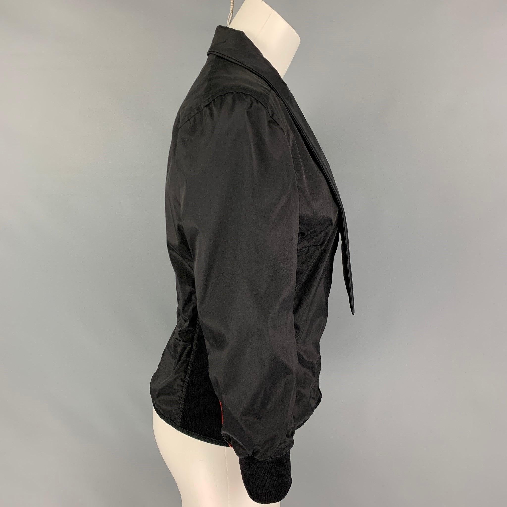 PRADA jacket comes in a black nylon with knitted panels featuring a reversible style, self tie up design, back sit pocket, and a full zip up closure. Made in Italy.
 Good
 Pre-Owned Condition. Light marks at front. As-Is.  
 

 Marked:  L  
 

