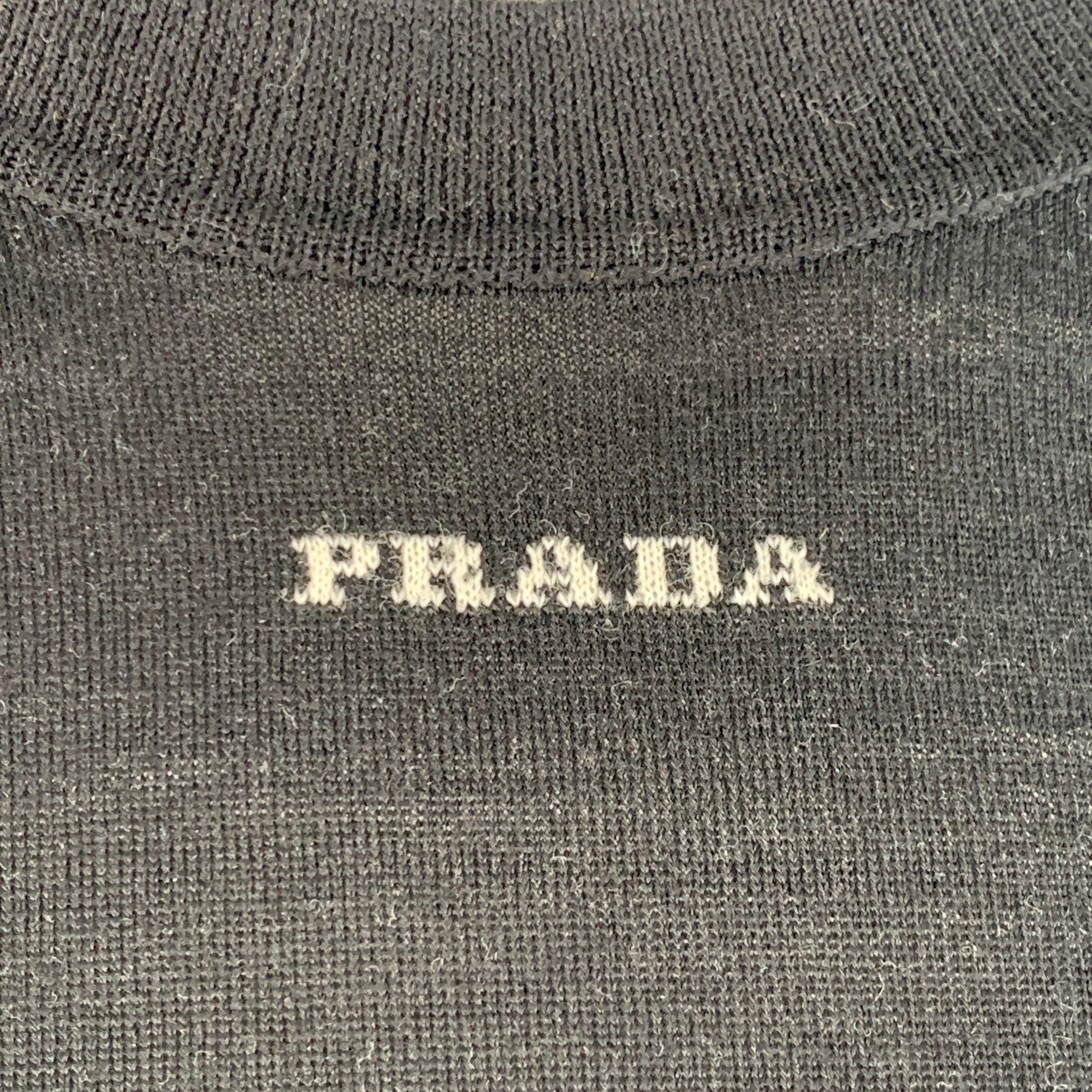 Pullover di Prada in jersey di lana nero con dettaglio del logo bianco sul collo anteriore, maniche lunghe e girocollo. Made in Italy.Ottime condizioni di usato. Minimo pilling. 

Contrassegnato:   IT 52 

Misure: 
 
Spalla: 20 pollici Petto: 46