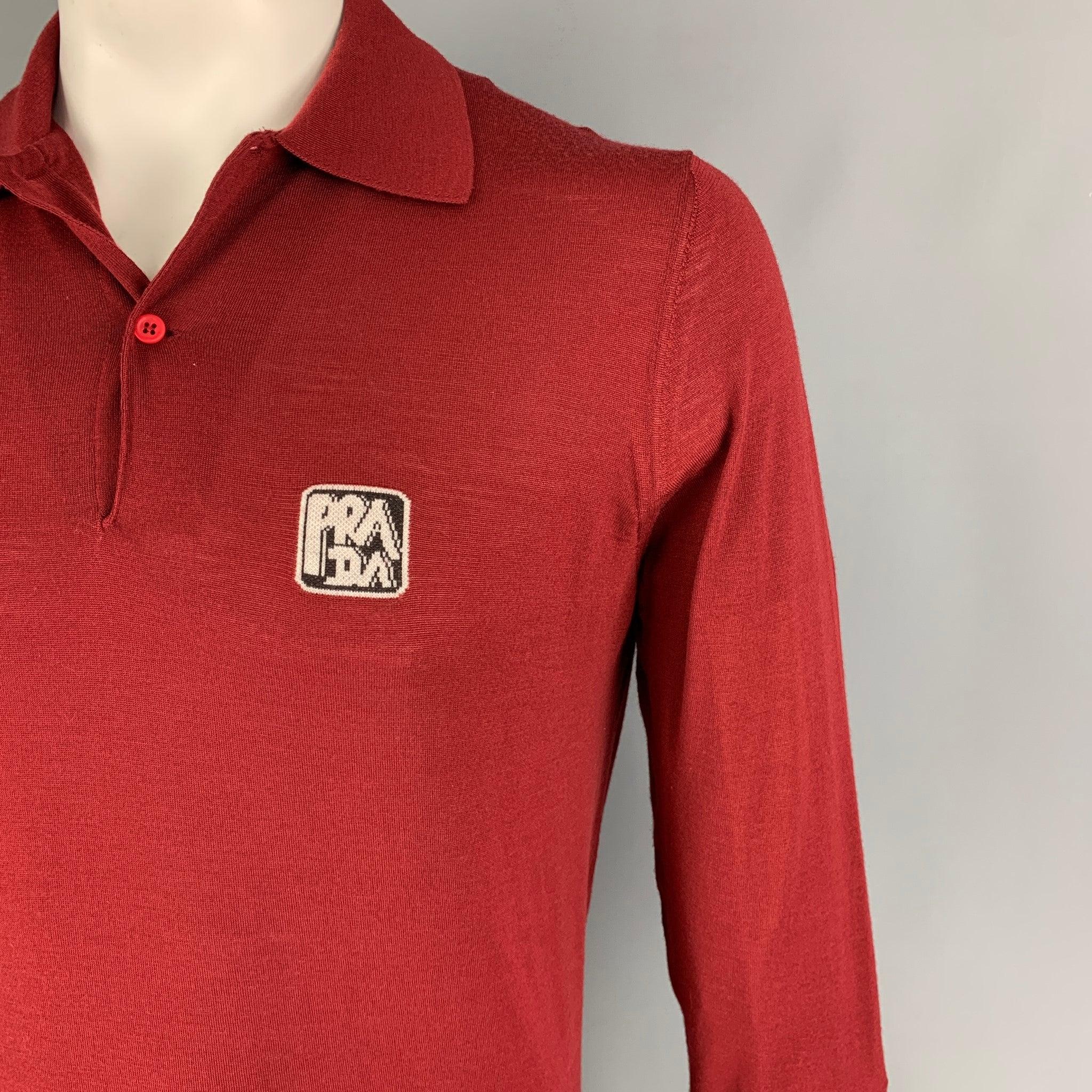 PRADA pullover comes in a burgundy knitted wool featuring a front logo, spread collar, and a half buttoned closure. Made in Italy.
Excellent
Pre-Owned Condition.  

Marked:   52 

Measurements: 
 
Shoulder: 17 inches Chest: 42 inches Sleeve: 29