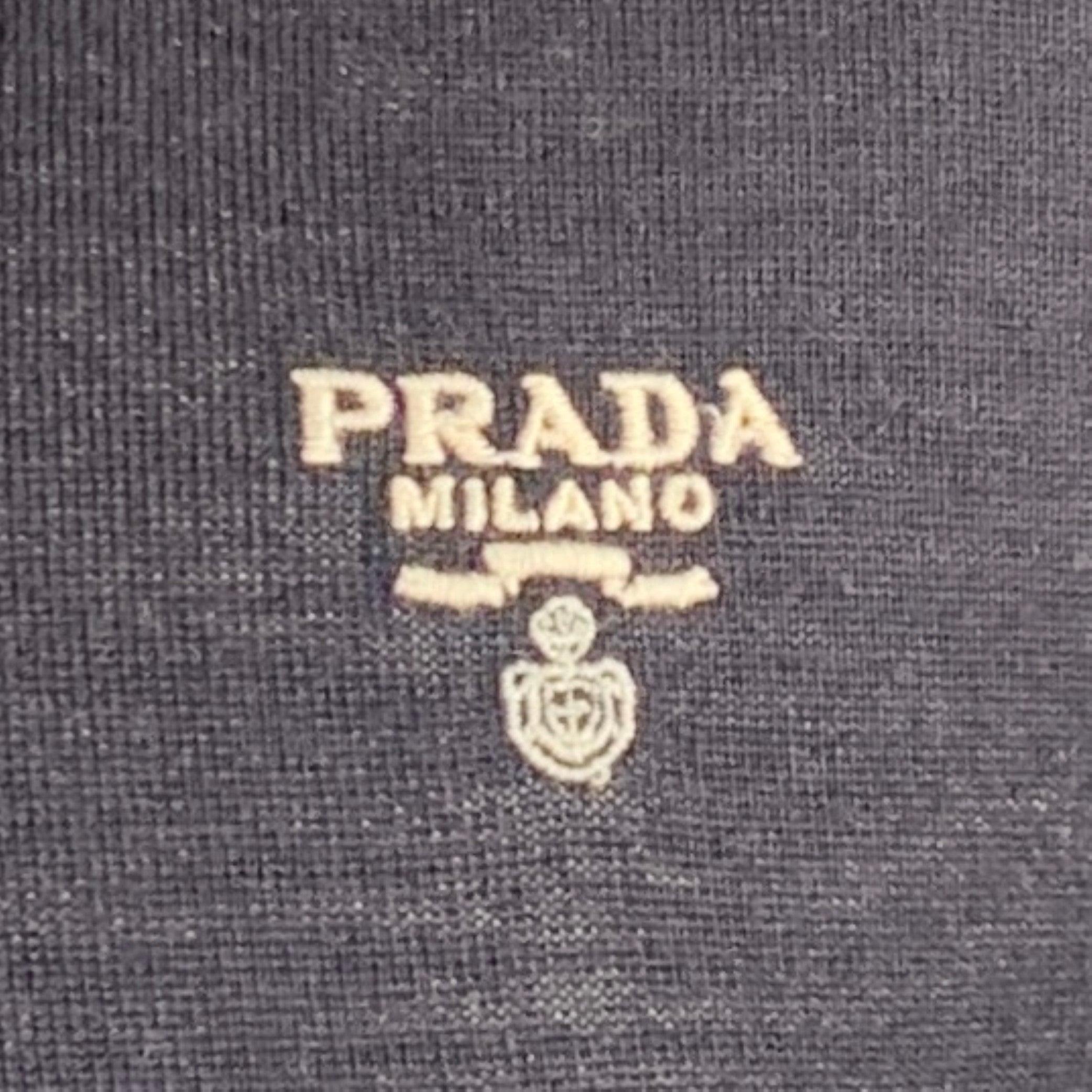 PRADA polo in a navy wool knit featuring white embroidered PRADA logo, spread collar, and half placket button closure. Made in Italy.Very Good Pre-Owned Condition. Minor pilling. 

Marked:   IT 52 

Measurements: 
 
Shoulder: 19 inches Chest: 44