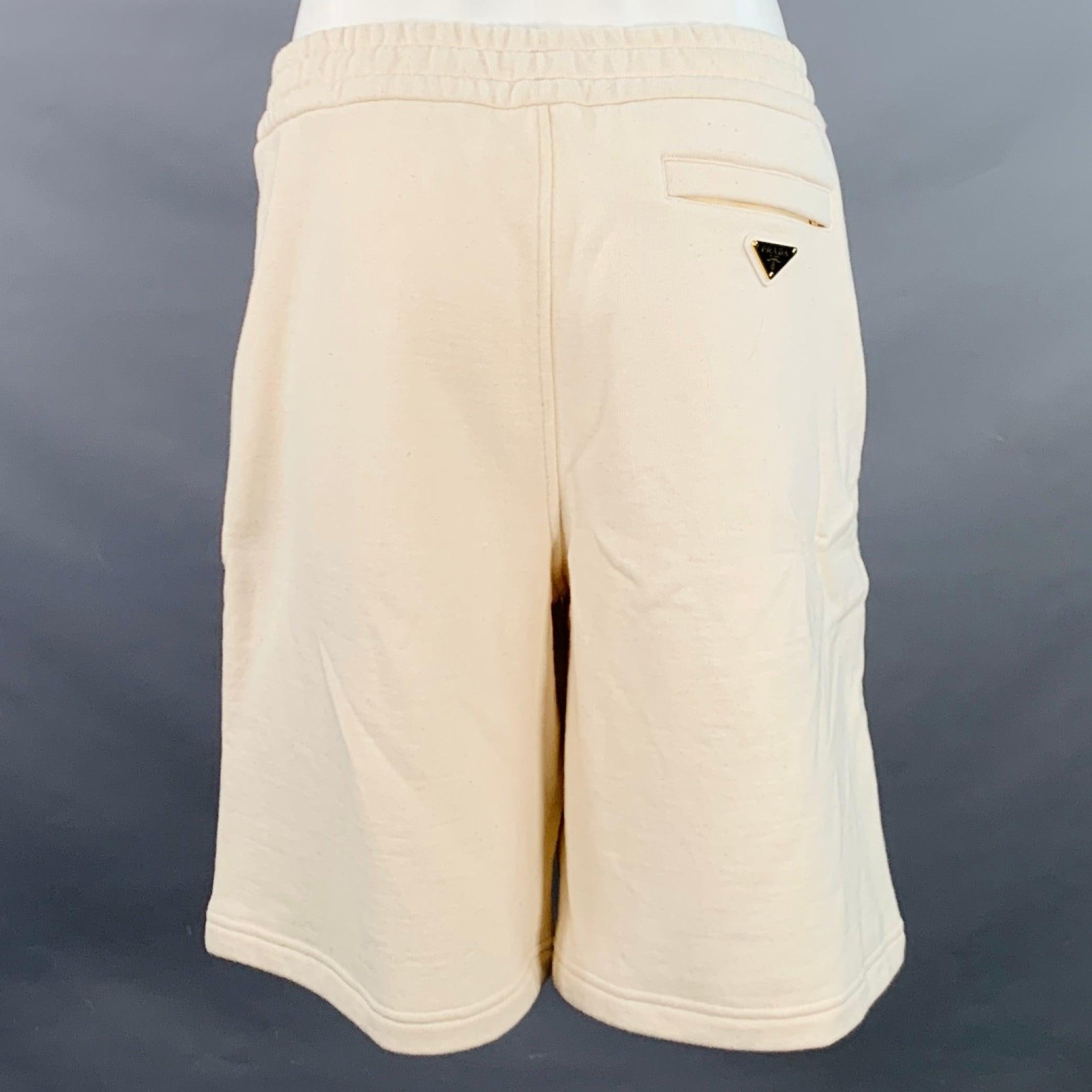 Short d'athlétisme PRADA en coton épais beige, doté d'un cordon de serrage à la taille et d'un logo triangulaire en métal. Fabriqué en Italie. Excellent état. 

Marqué :   M 

Mesures : 
  Taille : 33 - 38 pouces Taille : 12 pouces Entrejambe : 9.5
