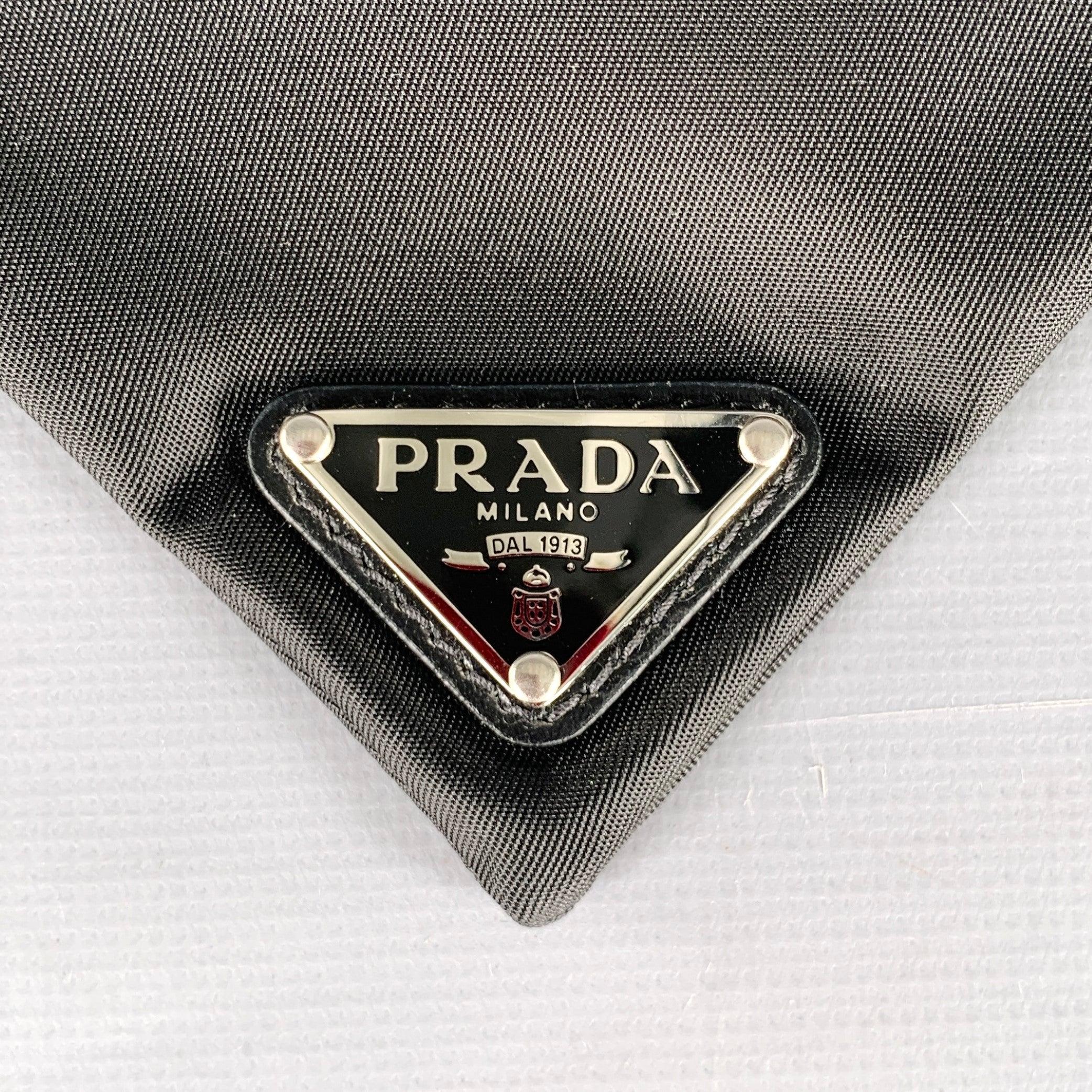 PRADA pet bandana in a black nylon fabric featuring silver tone metal Prada logo and buckle clasp closure. Comes with box.Excellent Pre-Owned Condition with Box. 

Marked:   MLength (with Clasp): 18 inches Height: 4.25 inches 
  
  
 
Sui Generis