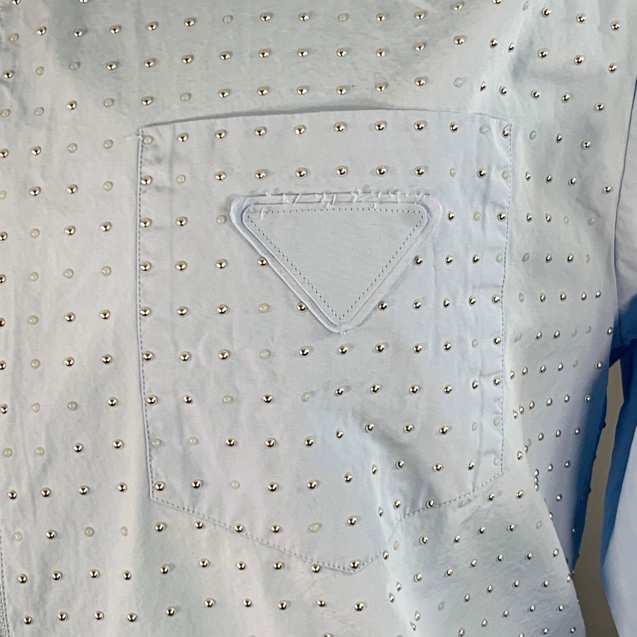 PRADA long sleeve shirt
in a blue cotton woven fabric featuring a studded design made up of silver tone metal and transparent studs, one pocket with triangle logo detail, and zip up closure. Made in Italy.Excellent Pre-Owned Condition. 

Marked:   M