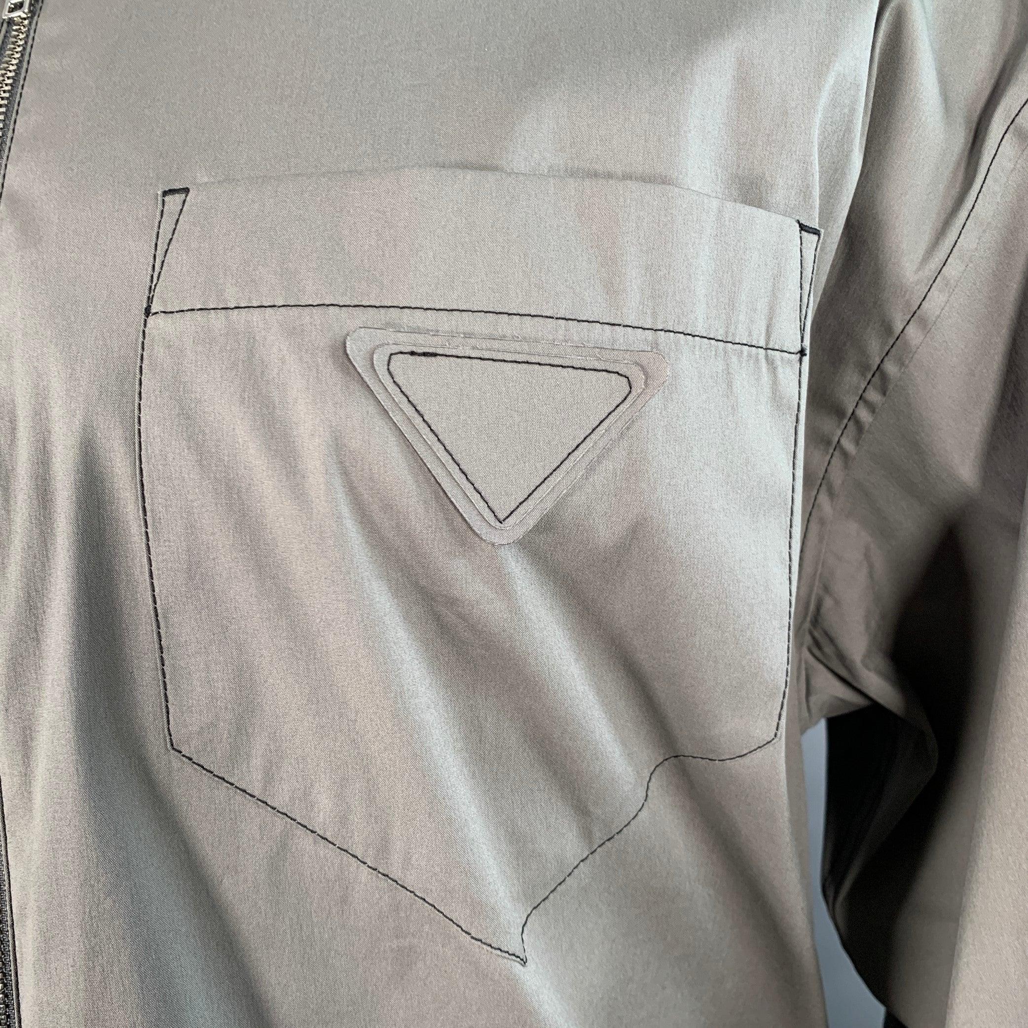Giacca camicia Prada
in tessuto misto cotone grigio sfoderato, con cuciture nere a contrasto, una tasca applicata con logo triangolare minimalista e chiusura con zip. Made in Italy. Eccellente condizione di usato.  

Contrassegnato:   M 

Misure: 
