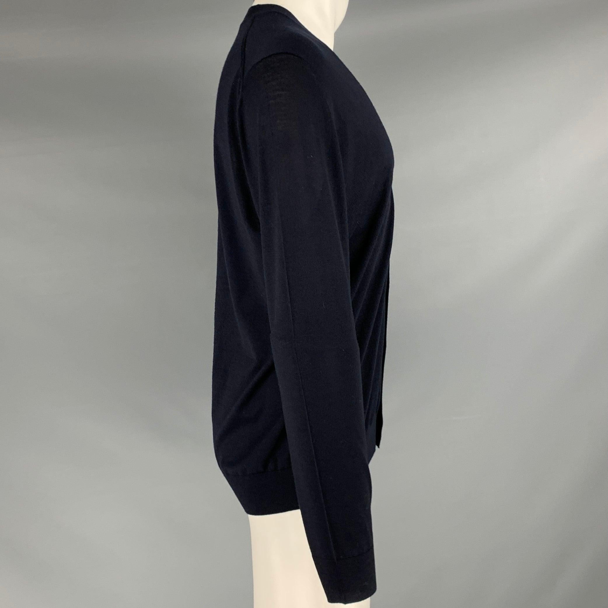 Cardigan PRADA
en tricot de laine marine, avec col en V et fermeture à boutons. Fabriqué en Italie. Très bon état. Signes d'usure modérés au dos. 

Marqué :   IT 52 

Mesures : 
 
Epaule : 20 pouces Poitrine : 42 pouces Manche : 26 pouces Longueur :