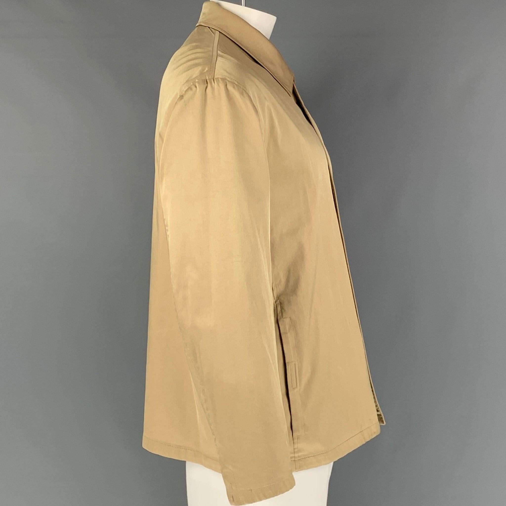 Ce manteau PRADA en soie mélangée beige est doté de poches frontales fendues et d'une fermeture à glissière. Fabriqué en Italie. Très bon état. Petites marques au col et aux manches. 

Marqué :   XL 

Mesures : 
 
Epaule : 21 pouces Poitrine : 52