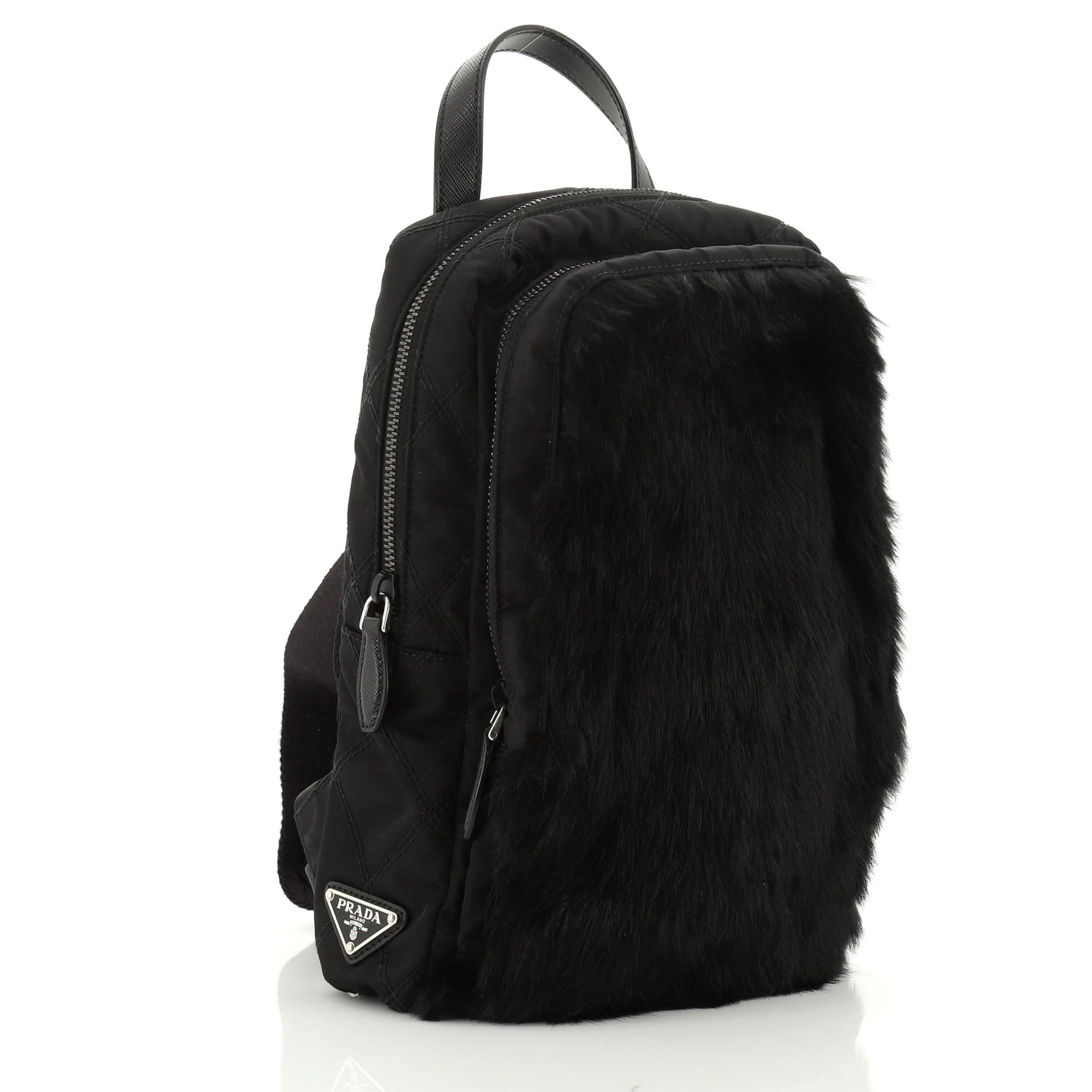 This Prada Sling Backpack Fur with Quilted Tessuto, crafted from black nylon and fur, features a leather top handle, adjustable strap, front zip compartment, and gunmetal-tone hardware. Its zip closure opens to a black nylon interior with side zip