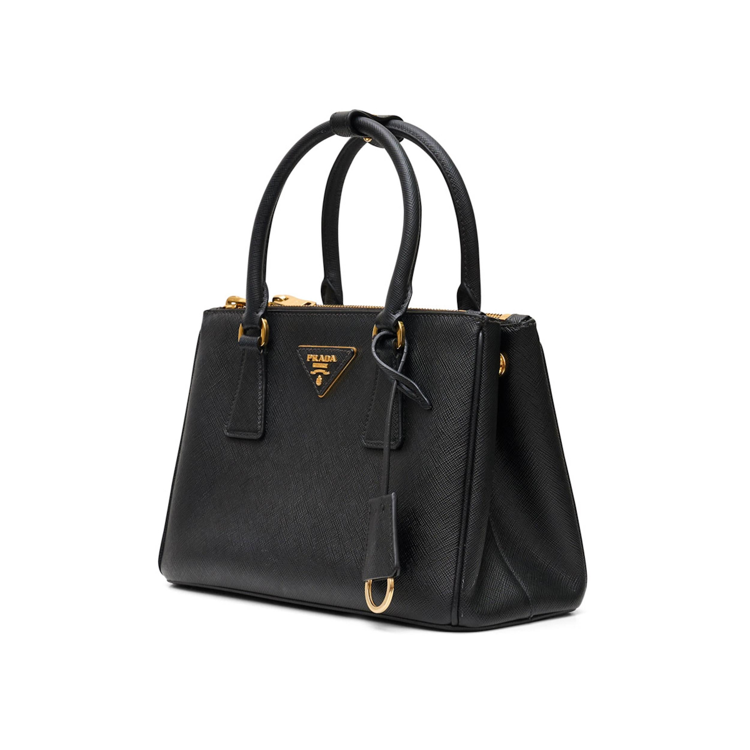 *Schwarz
*Saffiano-Leder
*Metallbeschläge
*Ledergriffe
*Lederdreieck mit Metallschriftzug auf der Vorderseite
*Abnehmbarer, verstellbarer Schulterriemen aus Leder
*Abnehmbarer Schlüsselring aus Leder
*Außentaschen mit