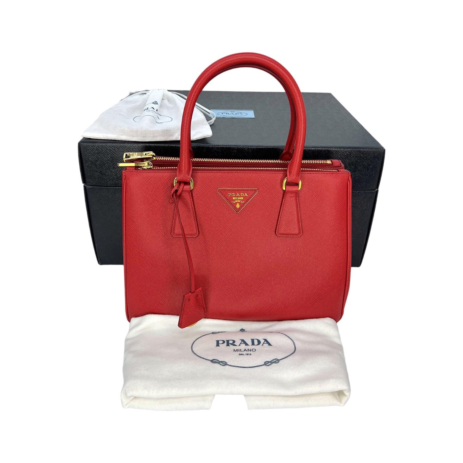 This Prada Small Double Zip Galleria Tote was made in Italy and it is finely crafted of a Saffiano Lux Leather exterior with gold-tone hardware features. It has dual rolled leather top handles. It comes with a attachable and adjustable shoulder