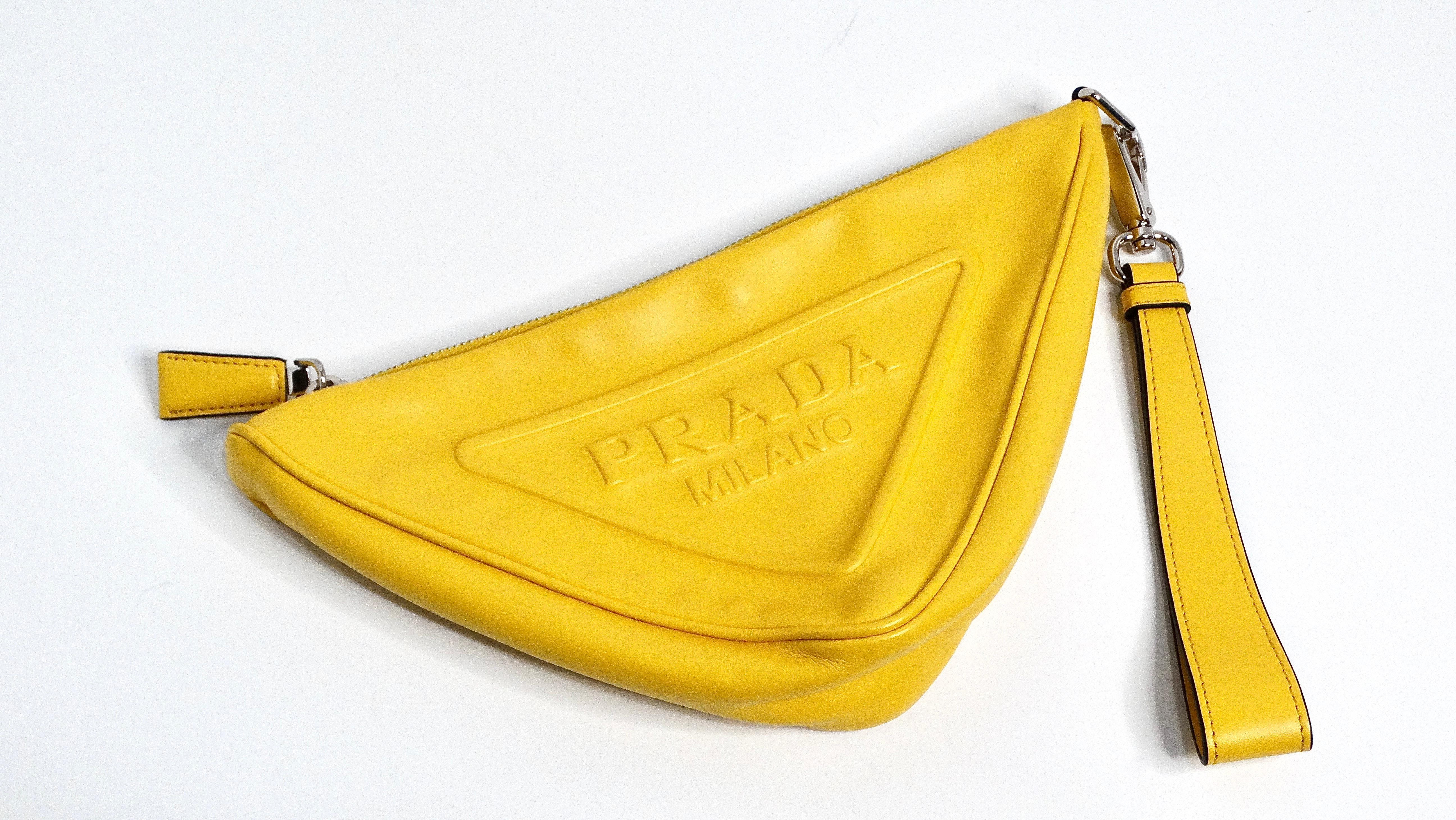 The Prada Sole Grace Yellow Triangle Leather Pouch is a vibrant and sophisticated accessory designed to add a splash of color to your daytime activities. Made from beautiful soft leather in a bold yellow hue, this pouch stands out with its sleek and