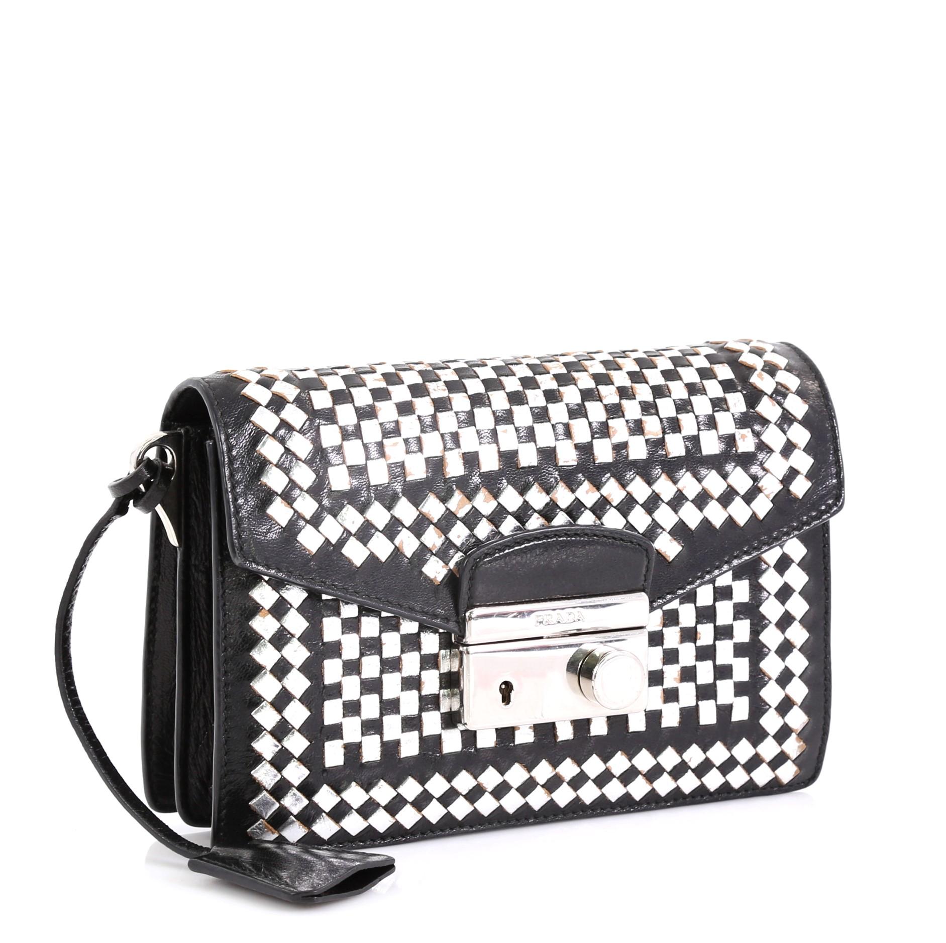 This Prada Sound Bag Woven Leather Mini, crafted in silver and black woven leather, features an adjustable shoulder strap and silver-tone hardware. Its flap with press-lock closure opens to a black leather interior with flap and slip pockets.