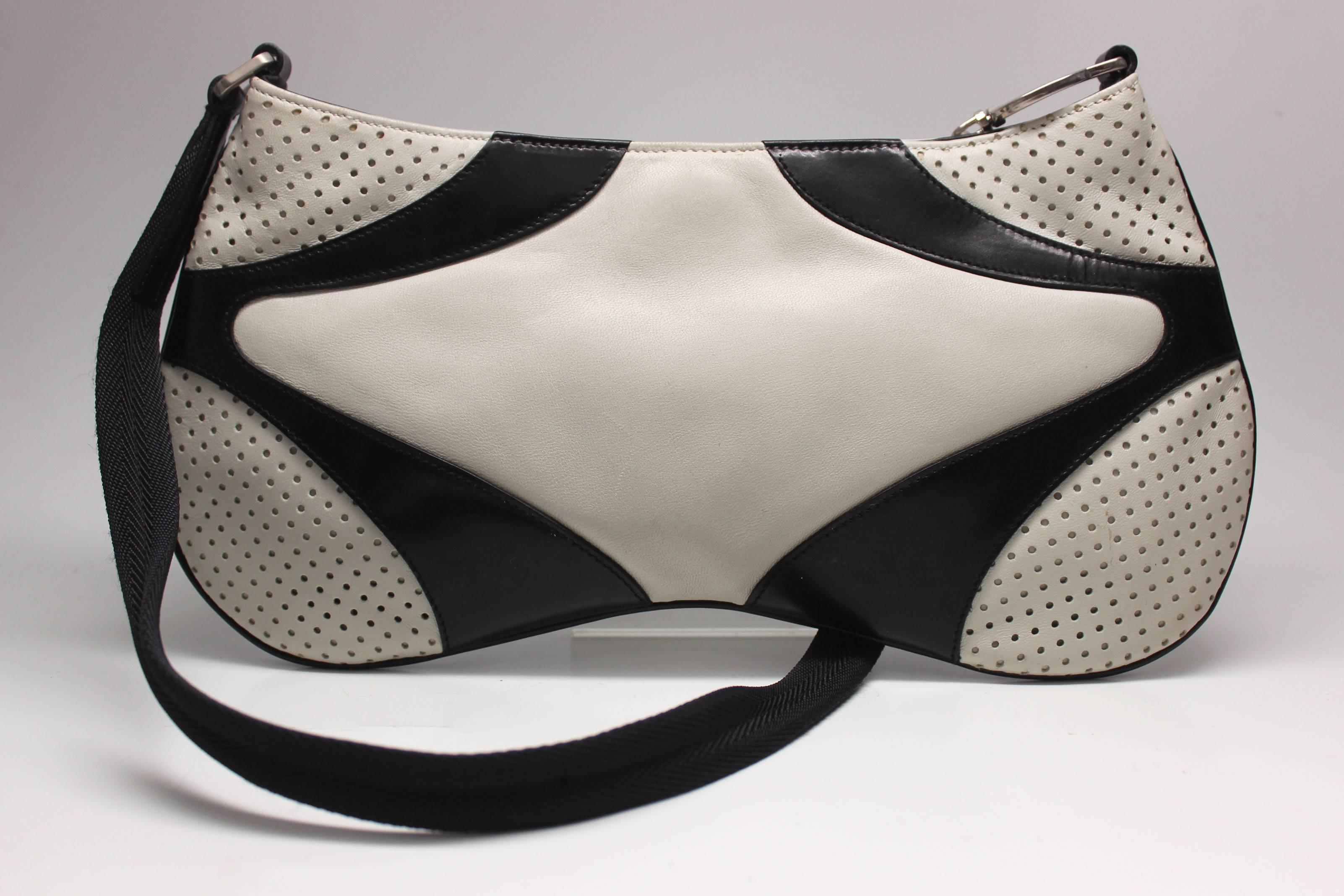 This sporty prada baguette has a mix of 3 different leathers. A supple creme, black and a creme perforated texture. The strap is black webbing with leather and metal hardware details.  The strap measures 24 inches.  There is a Prada stamp on the top