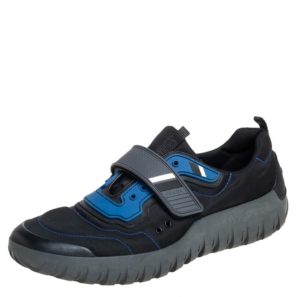 Confeccionado en piel azul negra, nailon y goma, este número de Prada es a la vez elegante y funcional. Se colocan sobre una suela de goma y vienen con tiras de velcro con el logotipo en los empeines. Combínalo con conjuntos informales para un look