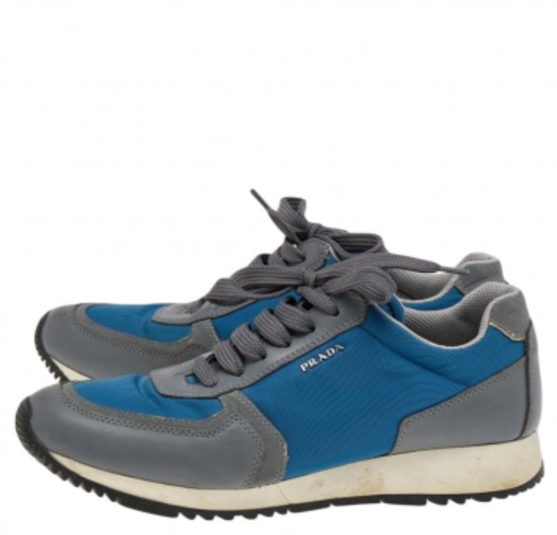 Présentées dans une silhouette low-top classique, ces baskets Prada Sport sont une combinaison parfaite de luxe, de confort et de style. Elles sont fabriquées en nylon et en daim dans les tons gris et bleu. Ces baskets sont ornées de logos,