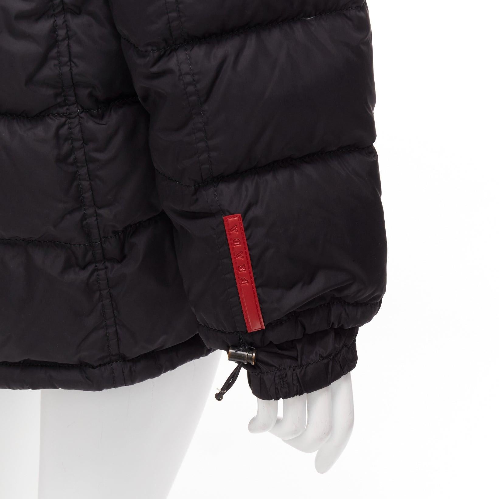 PRADA Sports black nylon down filled hooded puffer jacket IT40 S
Reference: CNPG/A00068
Brand: Prada
Designer: Miuccia Prada
Collection: Linea Rossa
Material: Nylon
Color: Black, Red
Pattern: Solid
Closure: Zip
Lining: Black Down
Extra Details: Red