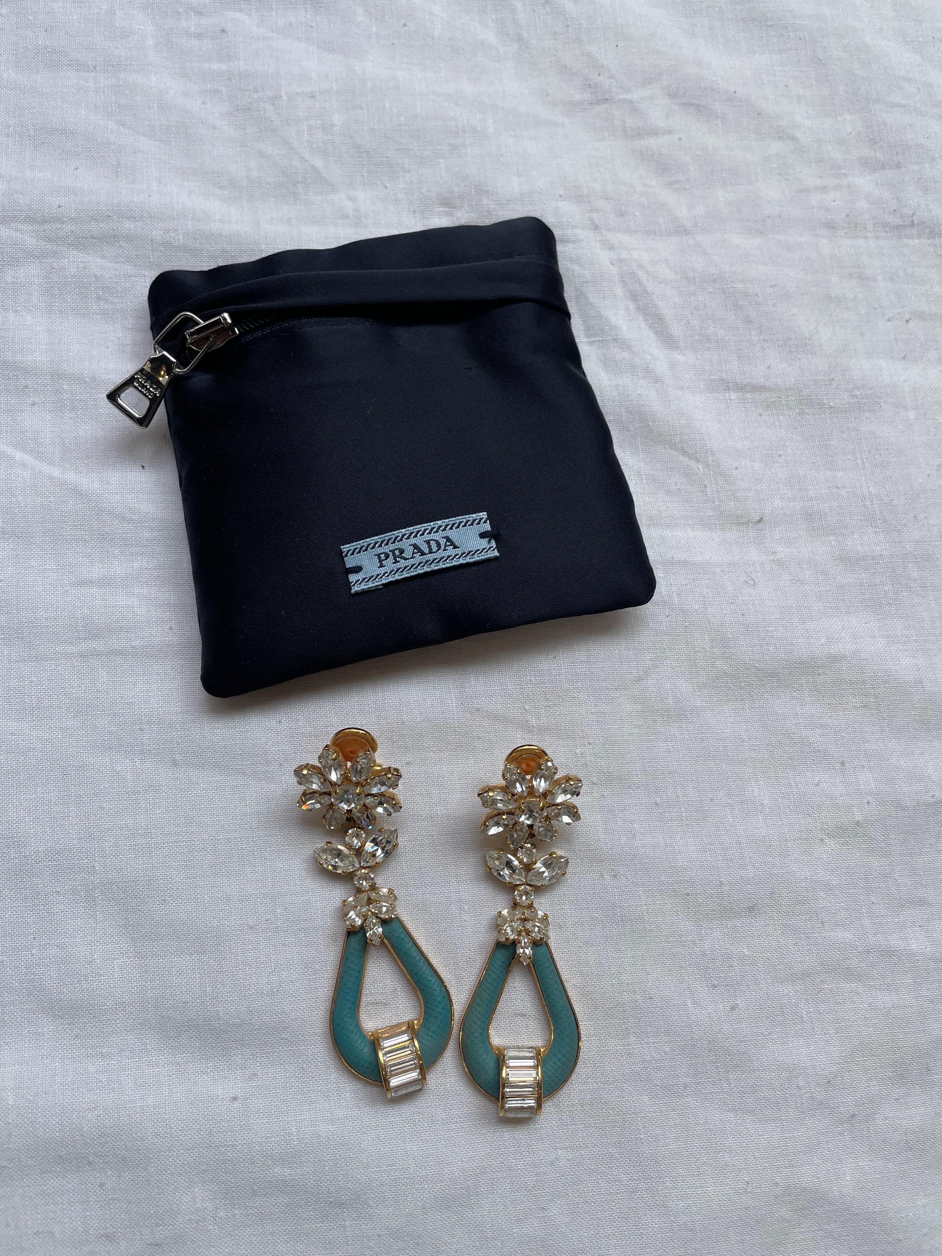 Prada spring summer 2014 earrings, collection inspired by the high jewelery of the 1940s. Turquoise saffiano leather details. They show some signs of use and a small stone is missing tending towards the inside so it is not too visible. 
Clip