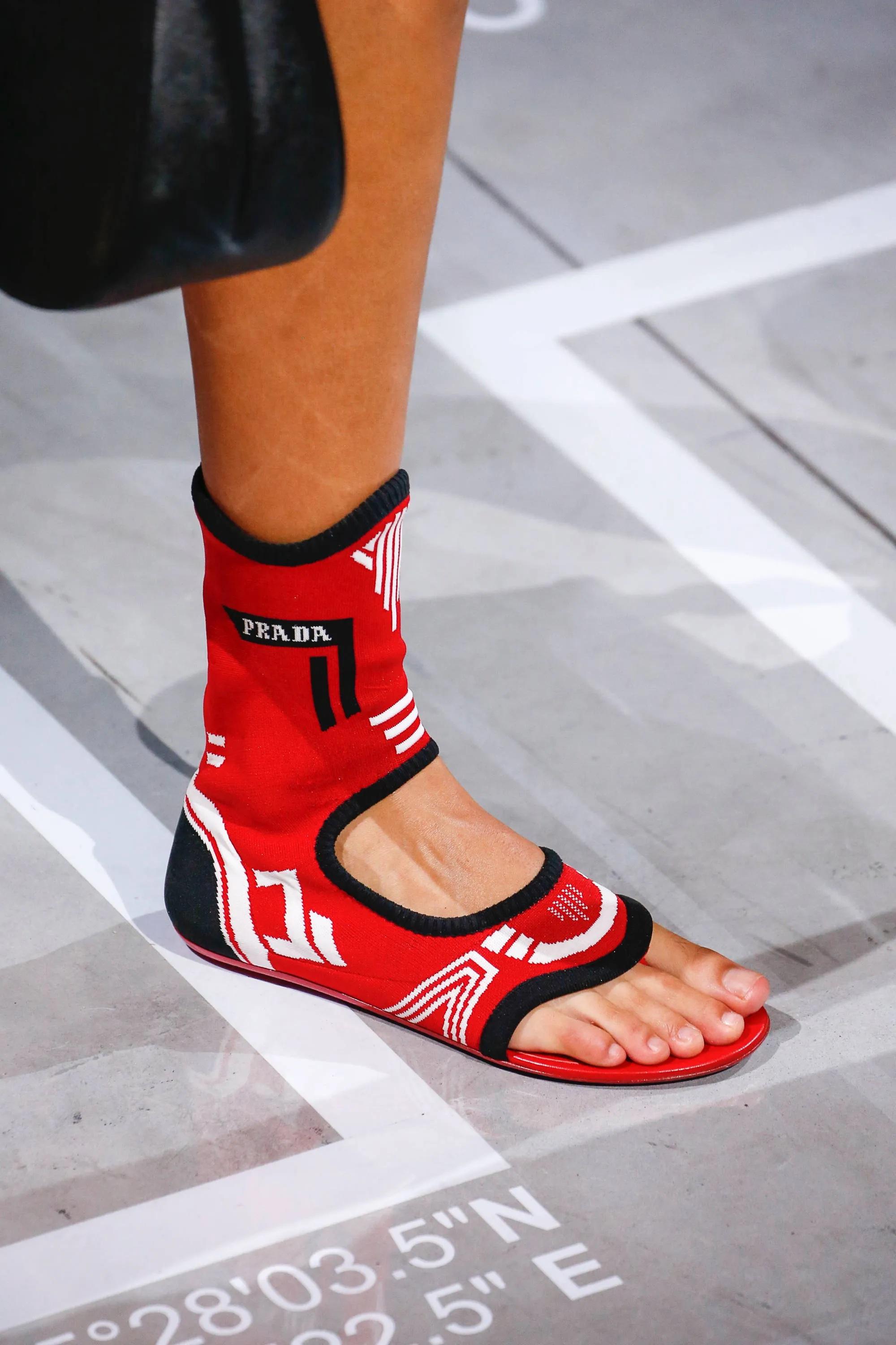 Black Prada flat knit lurex gladiator thong sandals as featured on the Spring/Summer '19 runway collection.

Hits partially up the calf and covers most of the foot.

White Prada logo knit on the outer sides.

Round toes.

Slip on.

Snug fit hugs the