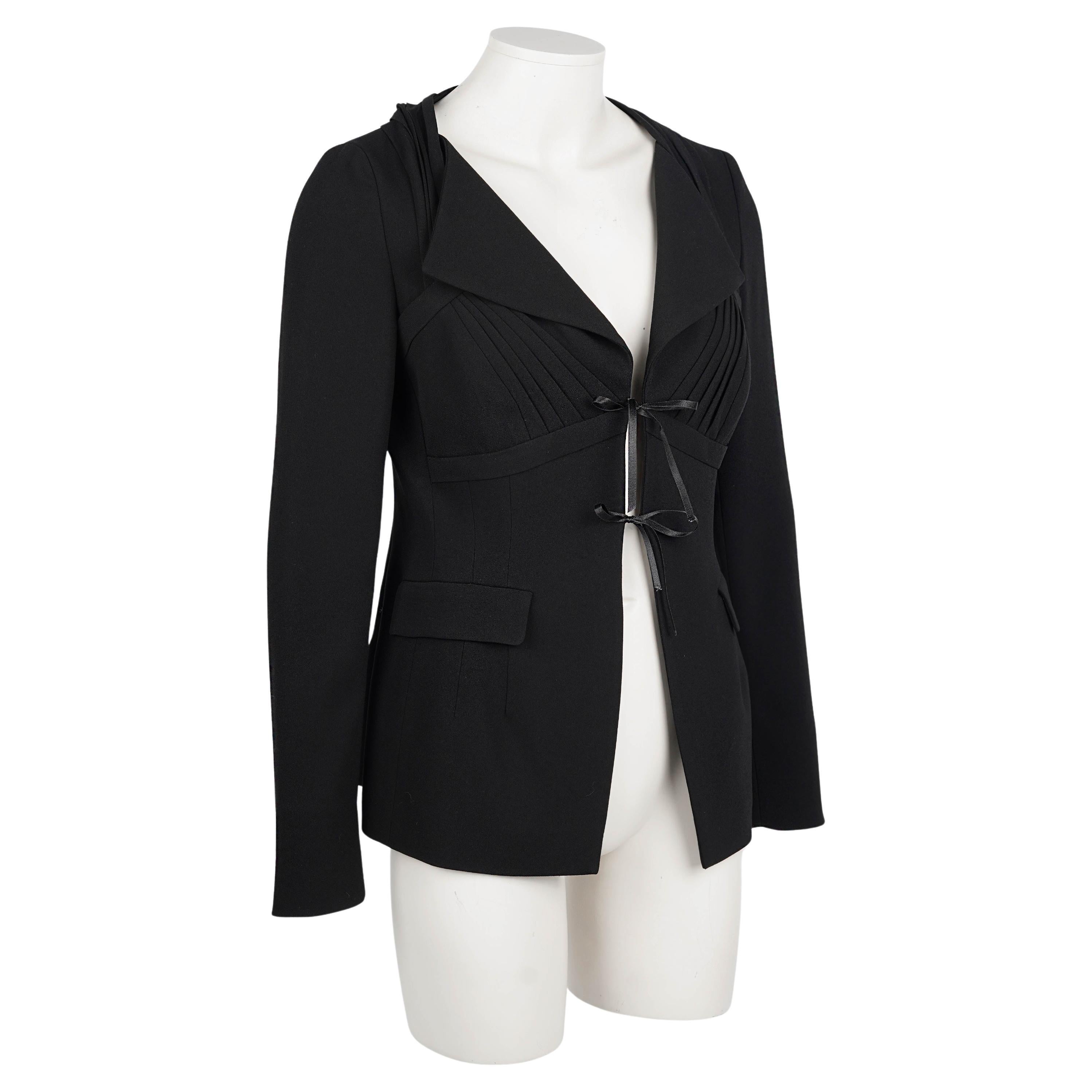 Questo raro blazer Prada, prodotto nel 2008, cattura la fusione di sartoria rigorosa e femminilità sovversiva tipica del marchio sotto la direzione creativa di Miuccia Prada.

Realizzato in un mix strutturato di acetato e poliestere di colore nero,