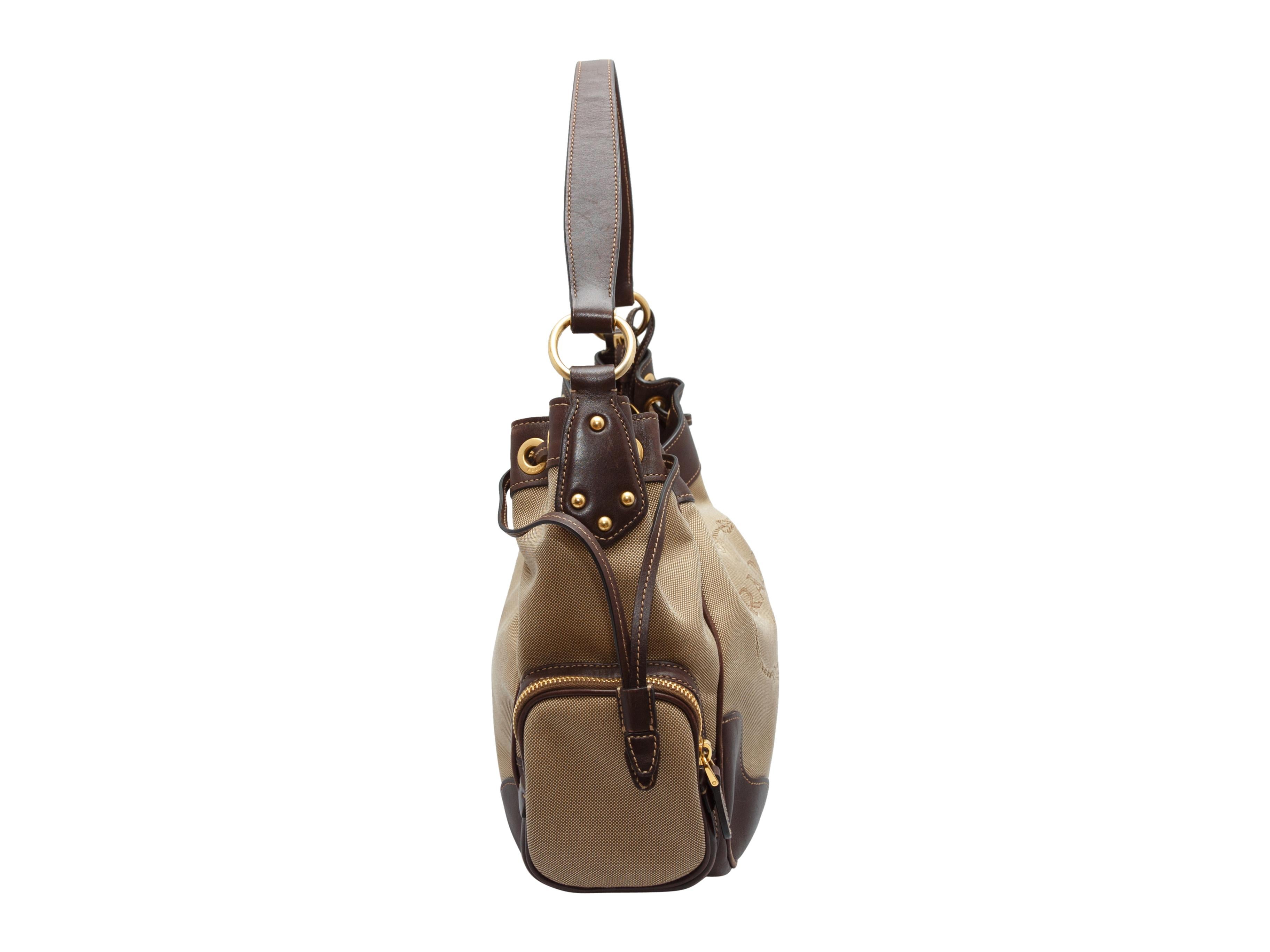 Product details: Tan and brown canvas logo handbag by Prada. Leather trim throughout. Gold-tone hardware. Dual zip pockets at sides. 13