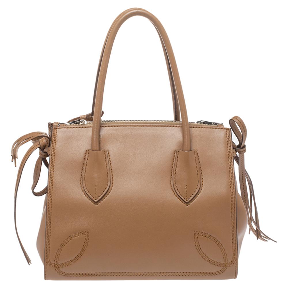 Remarkable for its brilliant design, this satchel from Prada will upgrade your style quotient. Crafted from tan leather, it features stitching details, ties on the sides, and a zip closure that opens to a spacious nylon-lined interior. This stylish