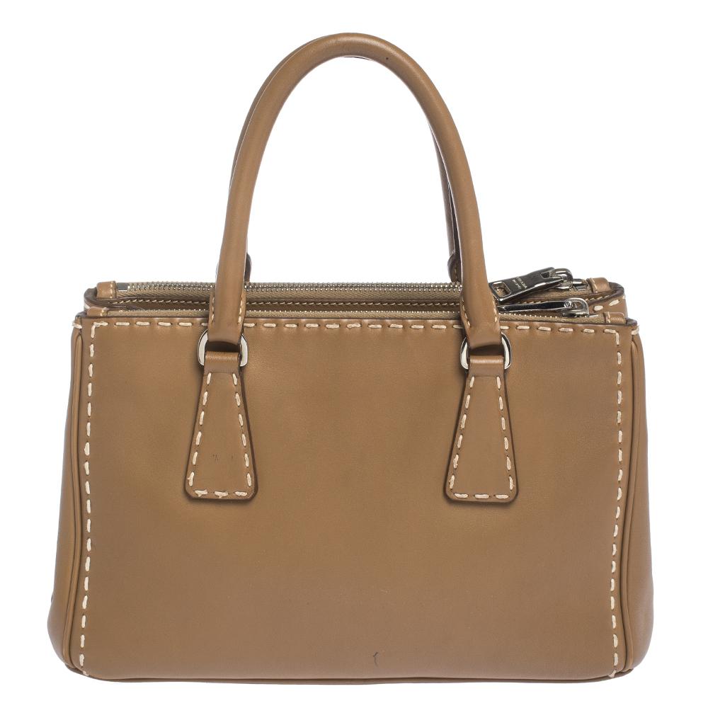 Feminine in shape and grand on design, this Double Zip tote by Prada will be a loved addition to your closet. It has been crafted from leather and styled minimally with silver-tone hardware. It comes with two top handles, two zip compartments and a