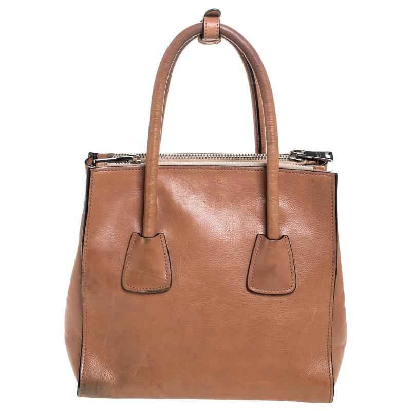 This lovely tote from Prada is crafted from leather and features a tan shade. It flaunts dual round handles, protective metal feet, and a spacious nylon-lined interior. Perfect to complement most of your outfits, this bag is worth every cent and