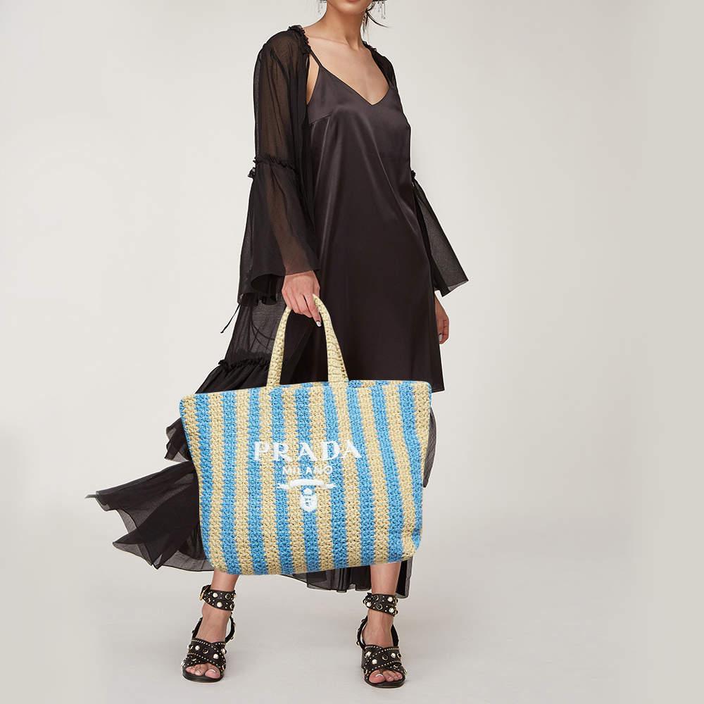 This Prada tote exudes effortless sophistication with its blend of natural straw and delicate pastel hues. Its spacious design effortlessly accommodates daily essentials while the crochet detailing adds a touch of artisanal charm. Perfect for sunny