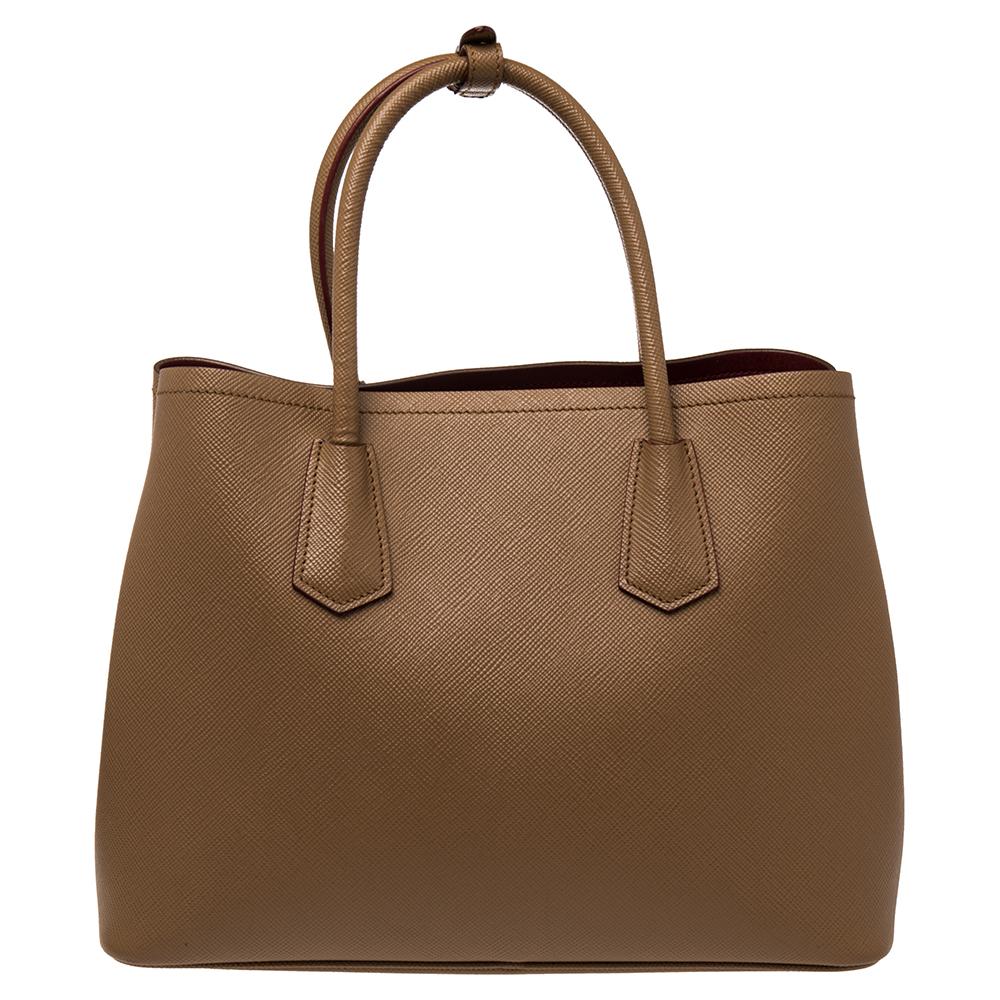 This lovely tote from Prada is crafted from Saffiano Cuir leather and features a tan shade. It flaunts dual round handles, an attached tag, protective metal feet, and a spacious leather-lined interior. Perfect to complement most of your outfits,