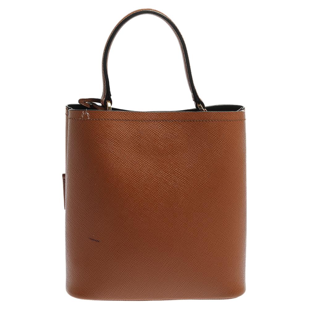Distinctive in design and style, this Panier bag from Prada definitely deserves to be yours! It has been crafted from tan Saffiano leather and features a single top handle and the brand logo at the front. It opens to a spacious leather-lined