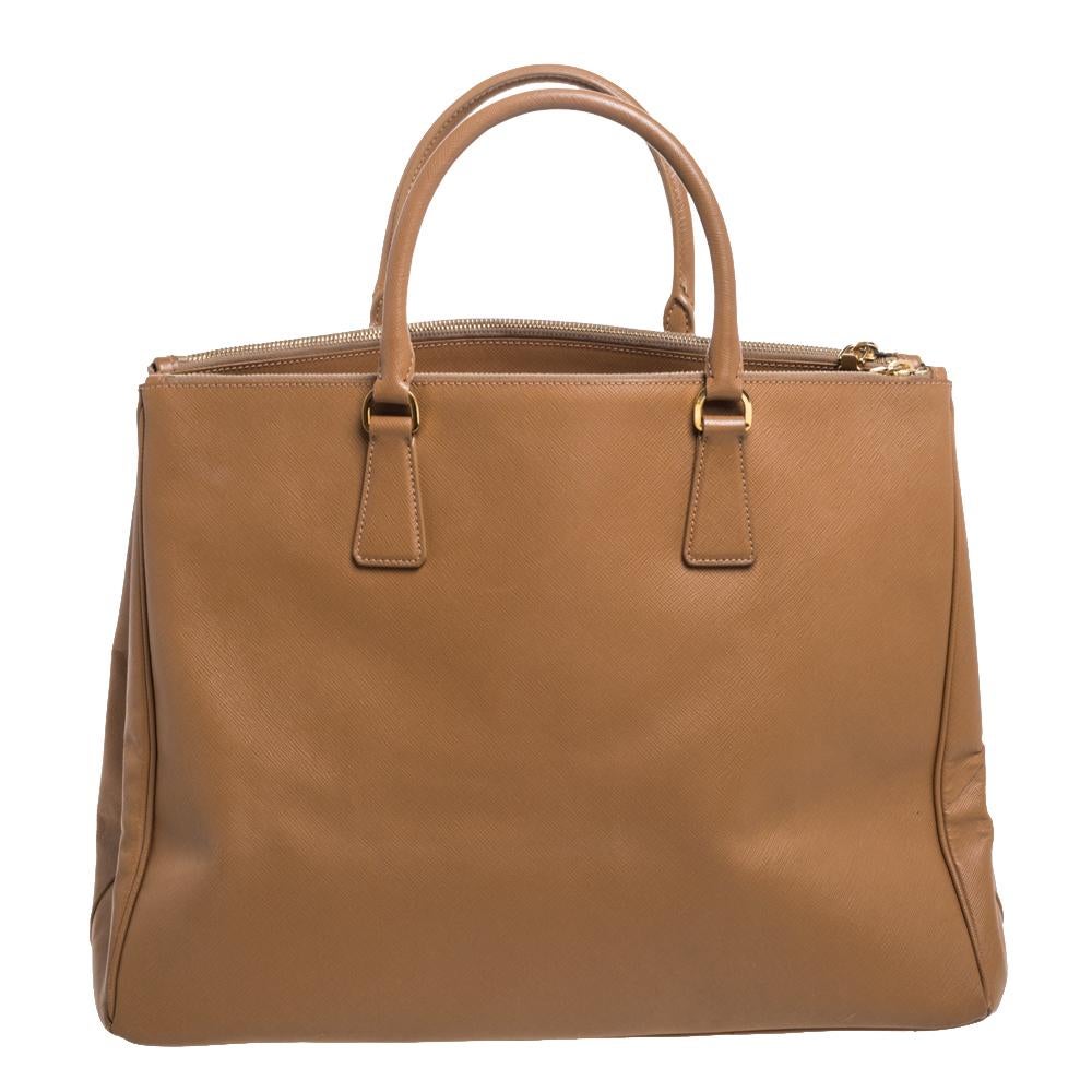 Feminine in shape and grand on design, this Executive Double Zip tote by Prada will be a loved addition to your closet. It has been crafted from leather and styled minimally with gold Tone hardware. It comes with two top handles, two zip