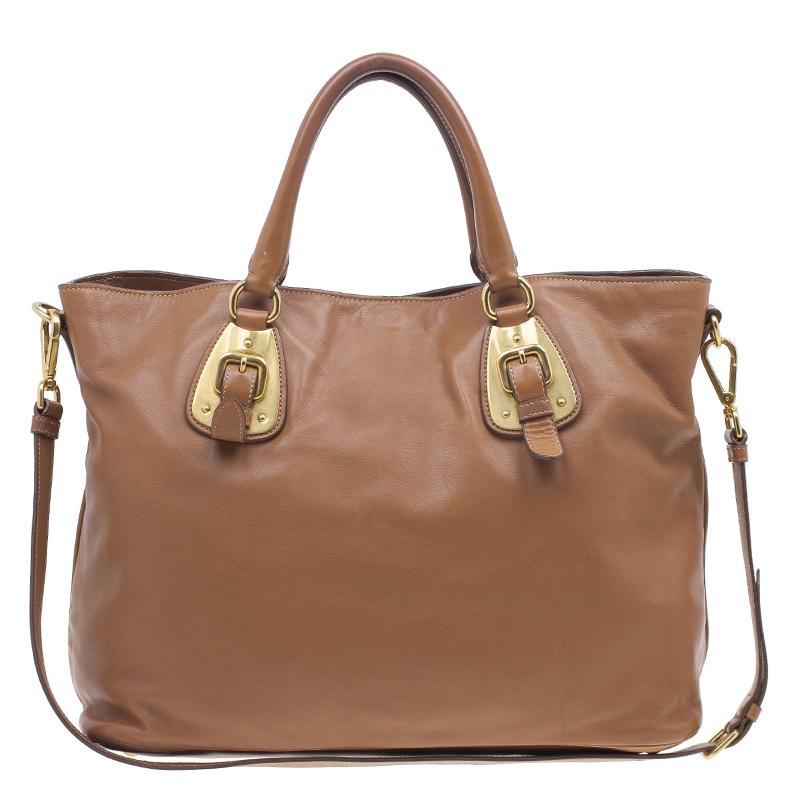 With its sophisticated design and subtle color, this soft calf leather tote by Prada is a great bag for everyday use. It is crafted from supple calf leather in a lovely shade of brown. The exterior features a front Prada logo, gold metal and buckle