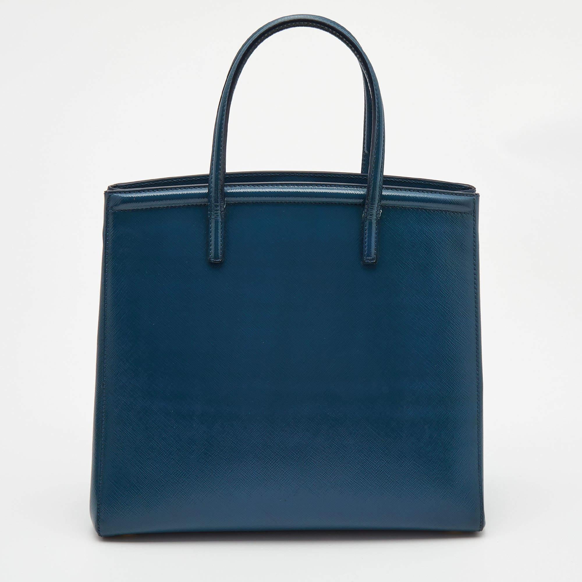 Masterfully created, this Prada tote is a style icon. Designed in a Saffiano Vernice leather body, it exudes style and class in equal measures. This delightful teal blue piece is held by two top handles and equipped with a spacious interior.


