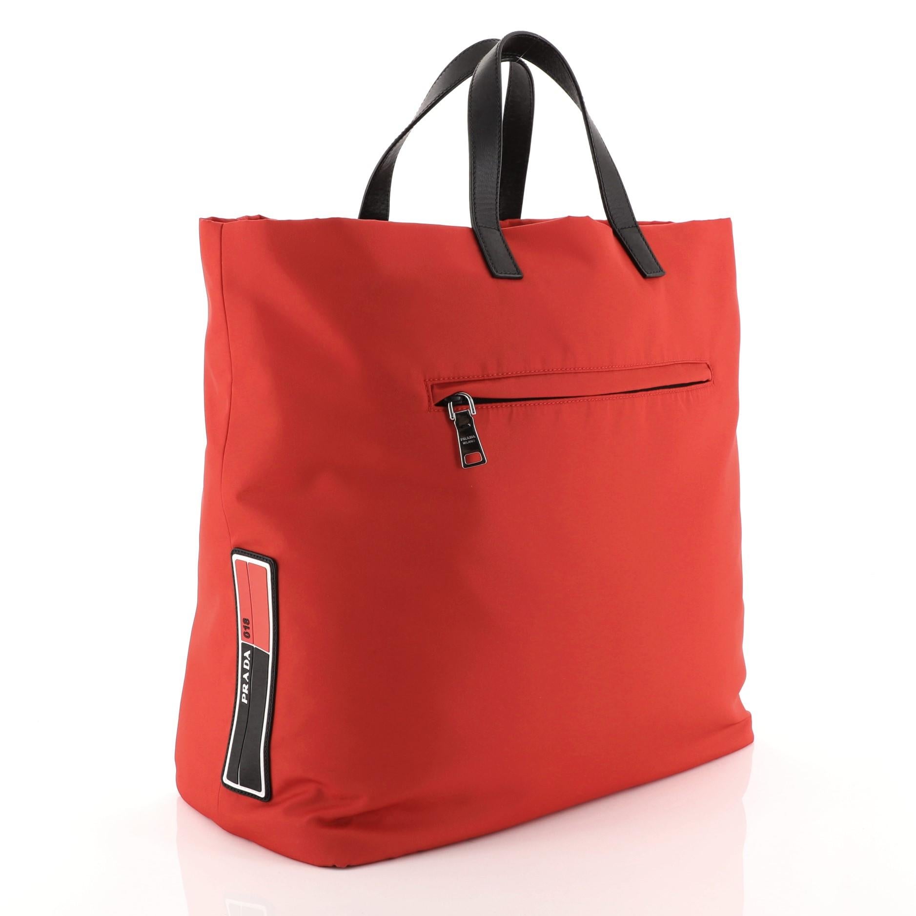 This Prada Technical Tote Tessuto Large, crafted from red tessuto, features dual top handles, exterior front zip pocket and silver-tone hardware. It opens to a red and black nylon interior with side zip pocket. 

Estimated Retail Price: