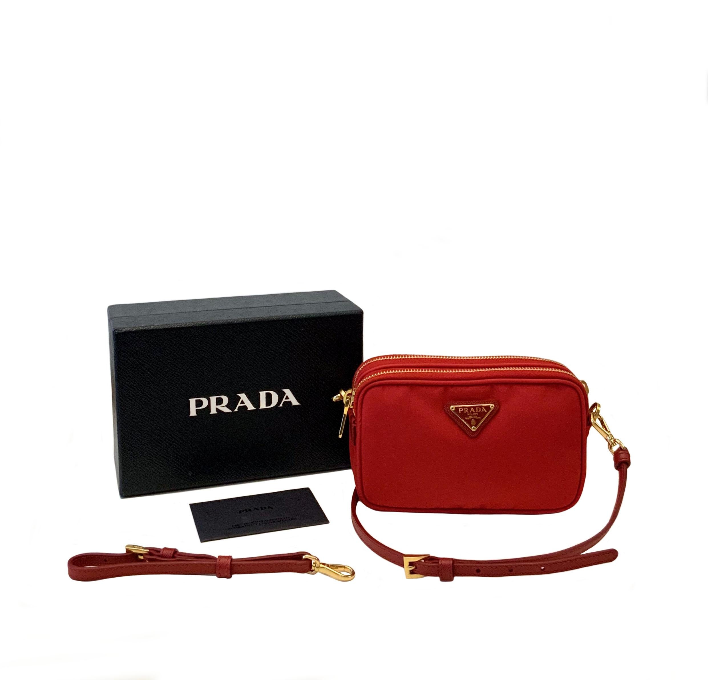 This pre-owned but new cross-body bag is crafted of Prada nylon in red. 
The bag features a long leather crossbody strap and an additional and removable single leather handle.
Two top zippers open to a red Prada monogram interior.

Material: