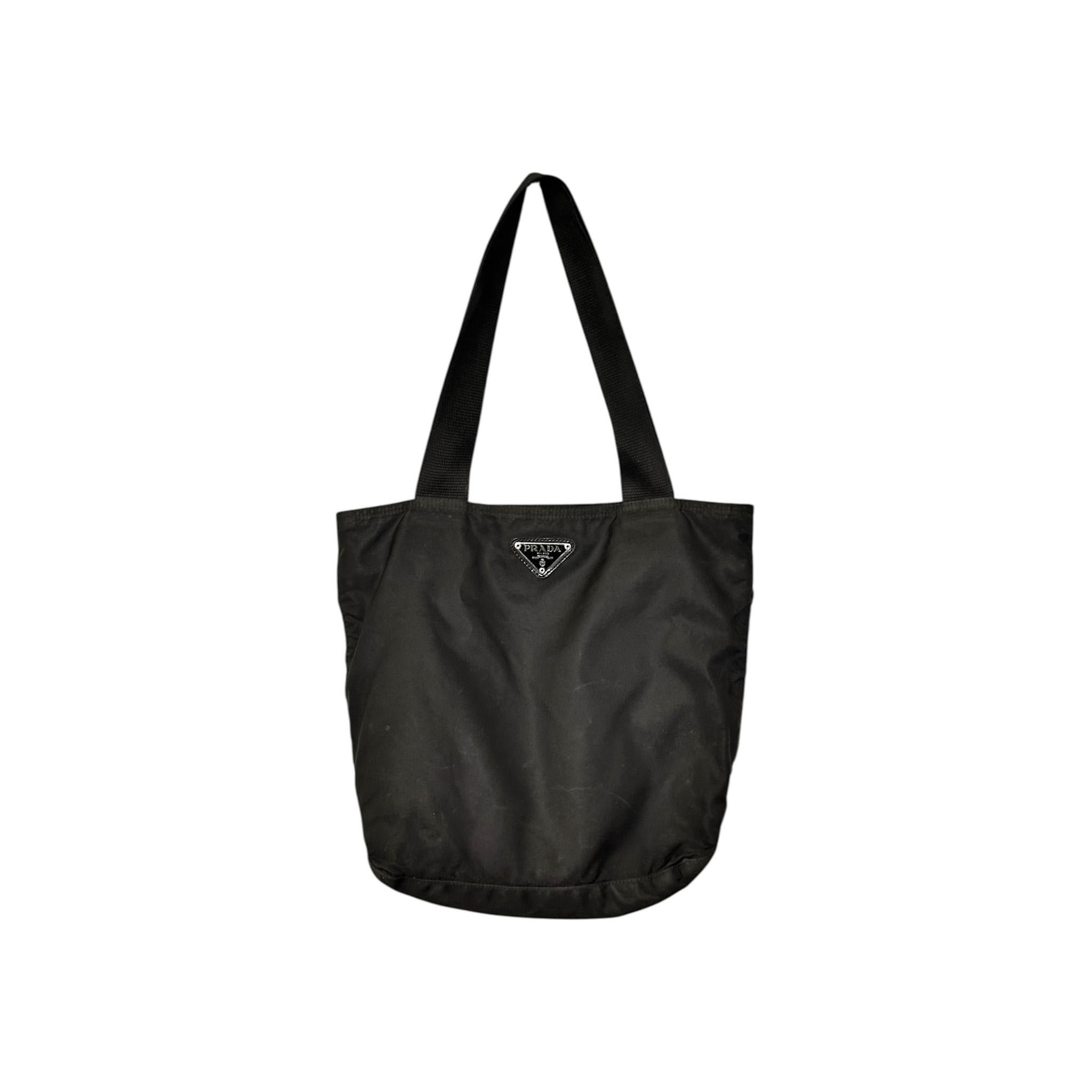 Ce fourre-tout vintage en nylon Prada Tessuto Triangle Logo est un accessoire intemporel et polyvalent conçu pour l'élégance au quotidien. Conçu en nylon noir résistant et doté de ferrures argentées, ce fourre-tout incarne la sophistication