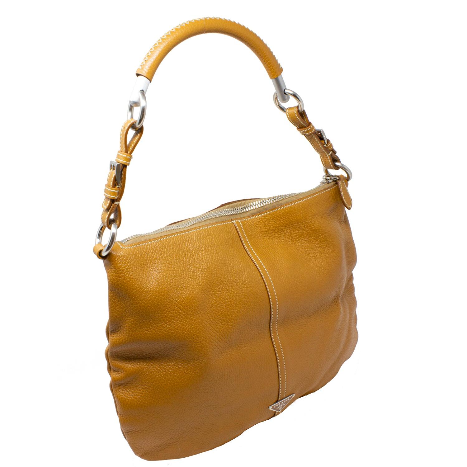 Stunning Prada shoulder bag crafted in a gorgeous natural tan leather, with a contrasting white wild stitch running down the center and on the handle shoulder guard. With silver-tone hardware, the top zipper opens up to a Logo Jacquard lining with a