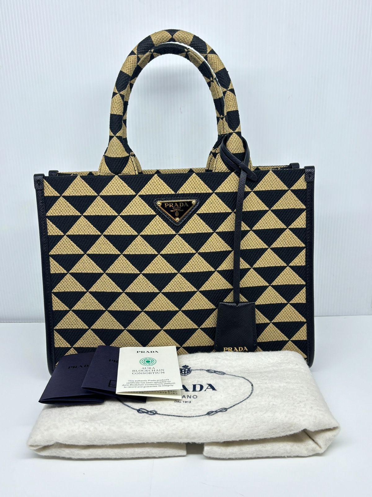 Prada small symbole tote in brown and black. Item is missing its long strap, but overall still in very good condition. Comes with its dust bag, clochette and care booklet.