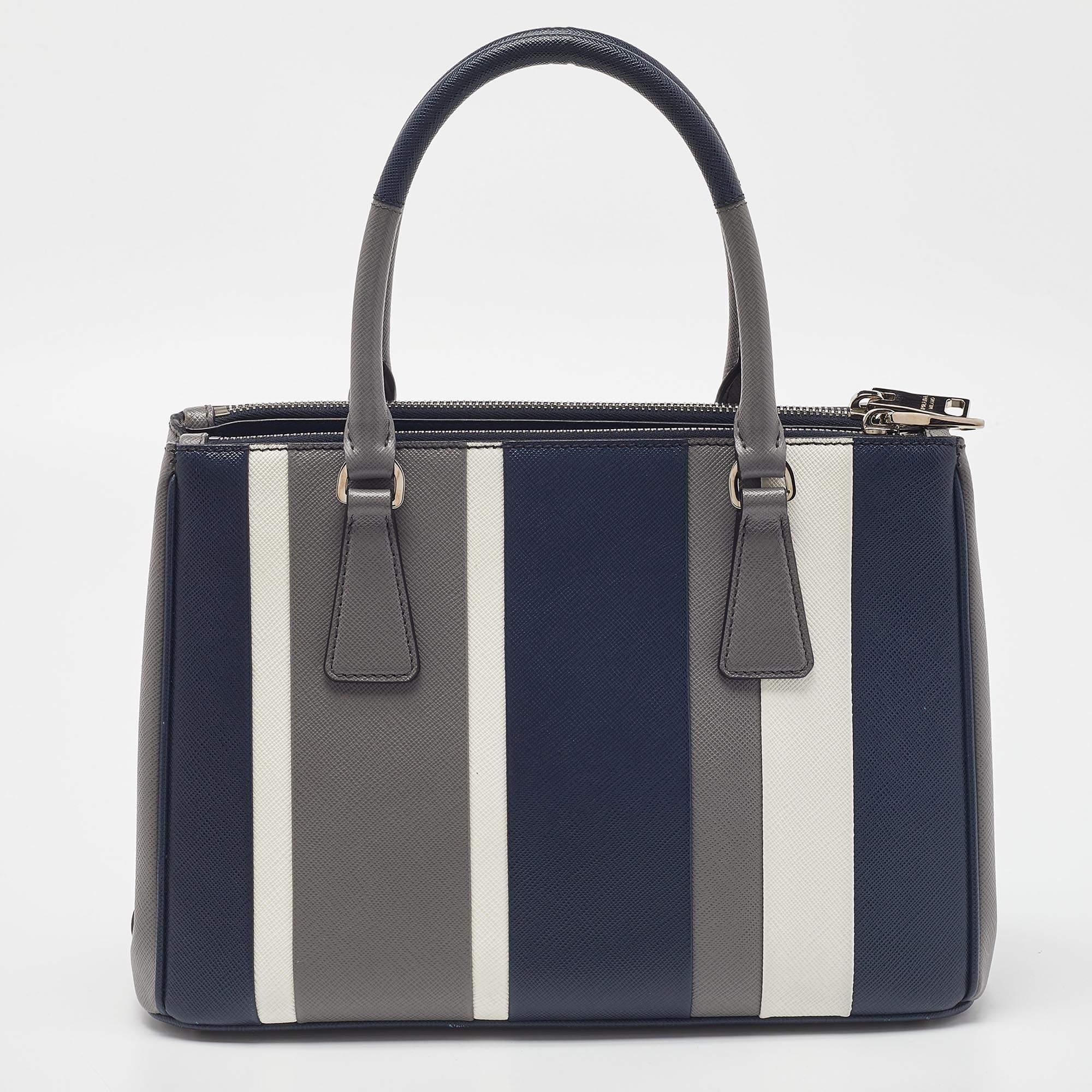 This Double Zip tote by Prada will be a loved addition to your closet. It has been crafted from Saffiano leather and styled with silver-tone hardware and tricolor. It comes with two top handles, two zip compartments, and a perfectly-sized main