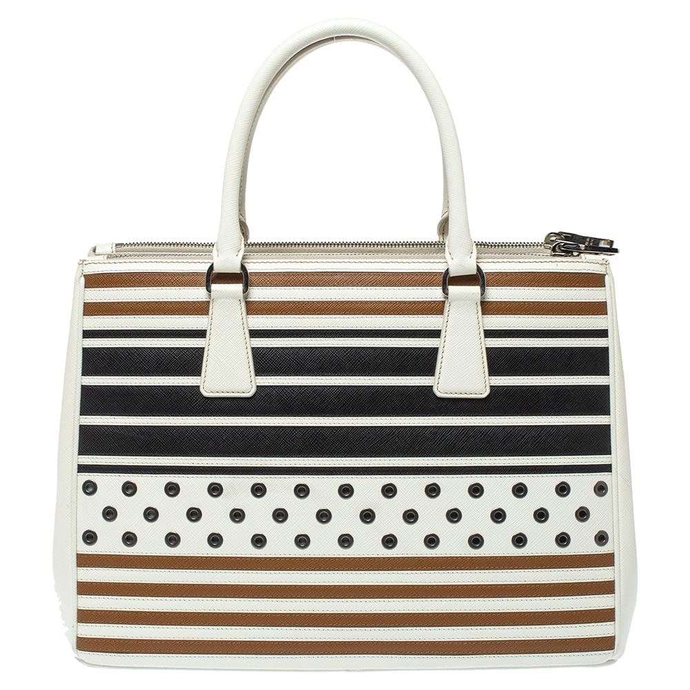 Feminine in shape and grand on design, this Double Zip tote by Prada will be a loved addition to your closet. It has been crafted from Saffiano leather and styled with stripes and rivets. It comes with two top handles and a perfectly-sized main