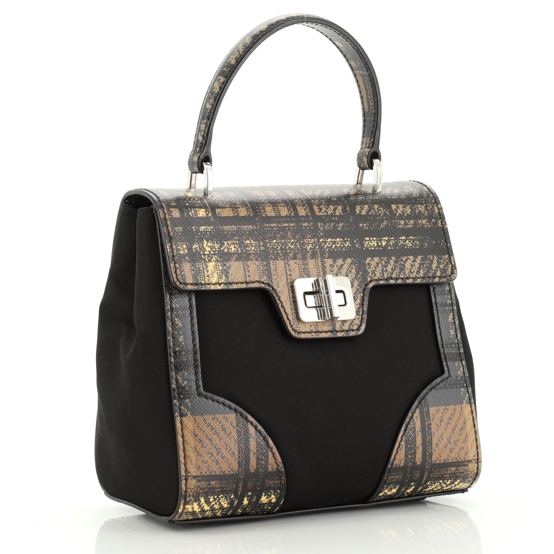 This Prada Turn Lock Top Handle Bag Printed Saffiano Leather with Tessuto Small, crafted from brown printed saffiano leather with black tessuto, features a leather top handle and silver-tone hardware. Its turn lock closure opens to a black fabric