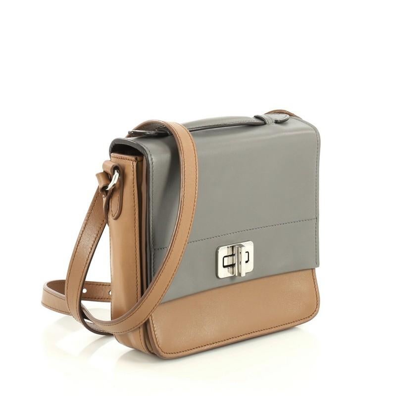 This Prada Turnlock Crossbody Bag City Calf Small, crafted in gray and brown calf leather, features an adjustable leather crossbody strap, pocket under flap, Prada logo at the back and silver-tone hardware. Its turn-lock closure opens to a brown