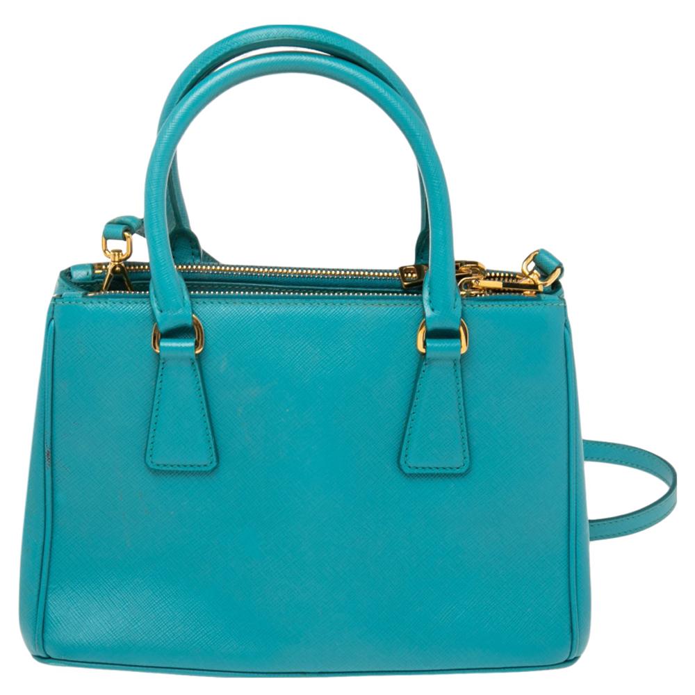 Feminine in shape and design, this Double-Zip Galleria tote by Prada will be a loved addition to your closet. It has been crafted using Saffiano Lux leather and styled minimally with gold-tone hardware. It comes with two top handles, nylon-lined