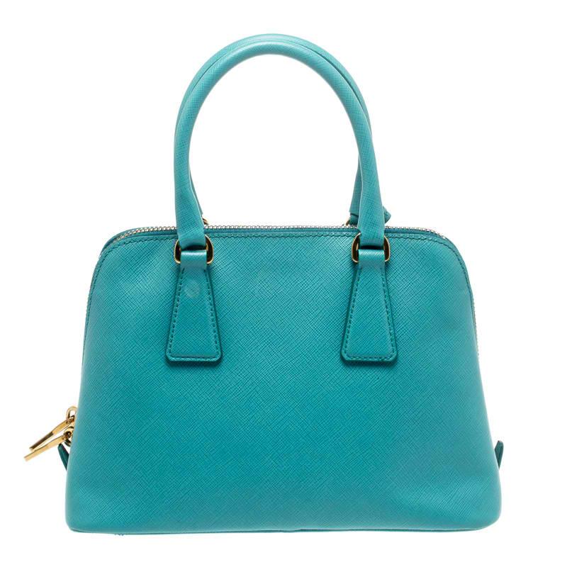 This stunning Promenade bag is high on appeal and style. Dazzling in a classy turquoise shade, the bag is crafted from Saffiano lux leather and features two rolled handles. The zip closure leads way to a nylon interior with enough space for your