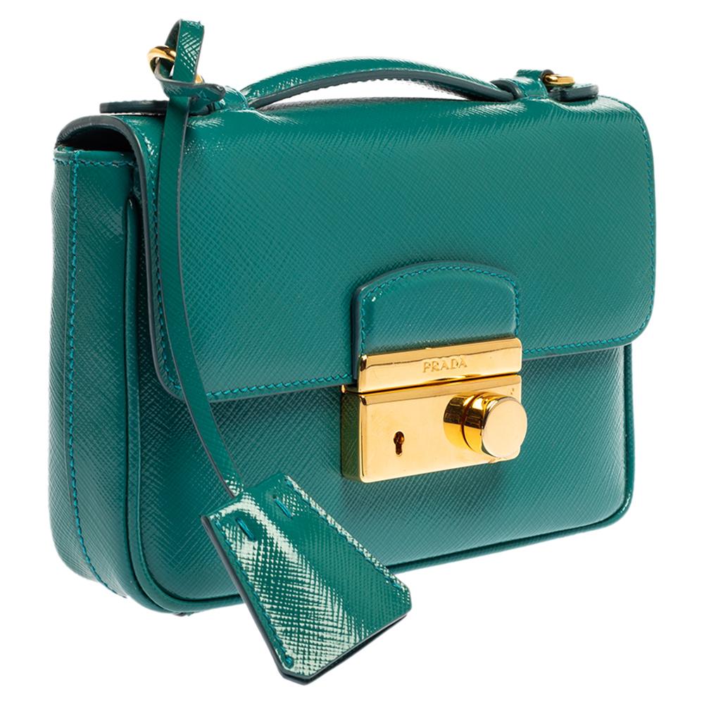 This bag exhibits Prada's exquisite approach to design. Beautiful Saffiano Vernic leather has been used to craft this bag. It comes in a turquoise hue and features a front flap with gold-tone closure. It opens to a nylon interior with enough space