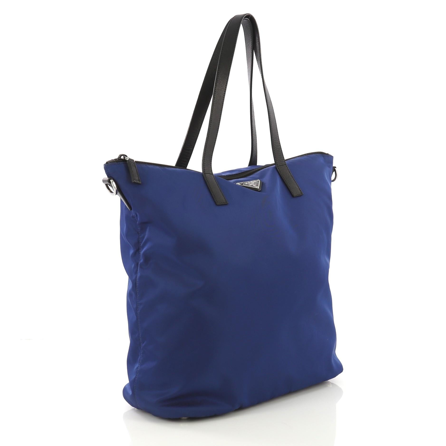 This Prada Vela Convertible Tote Tessuto Medium, crafted from blue tessuto, features dual top handles, triangle Prada logo at the center, and silver-tone hardware. Its zip closure opens to a black fabric interior with zip and slip pockets.