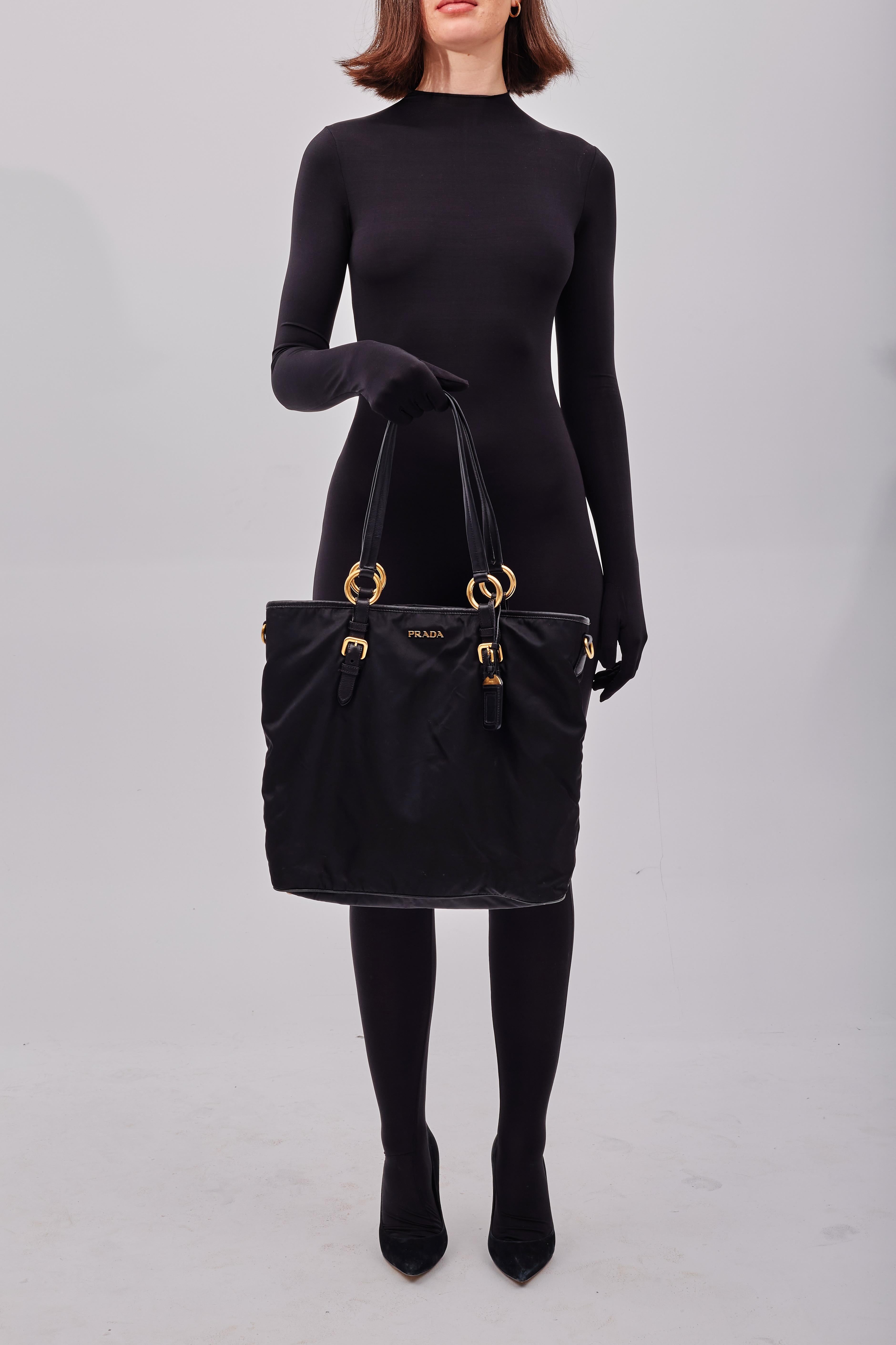 This large prada shopping bag is made of black nylon canvas with golden hardware. The bag is equipped dual black leather shoulder straps, snap closure and canvas logo lining with an  internal zip pocket. Vintage.

Color: Black
Material: nylon with