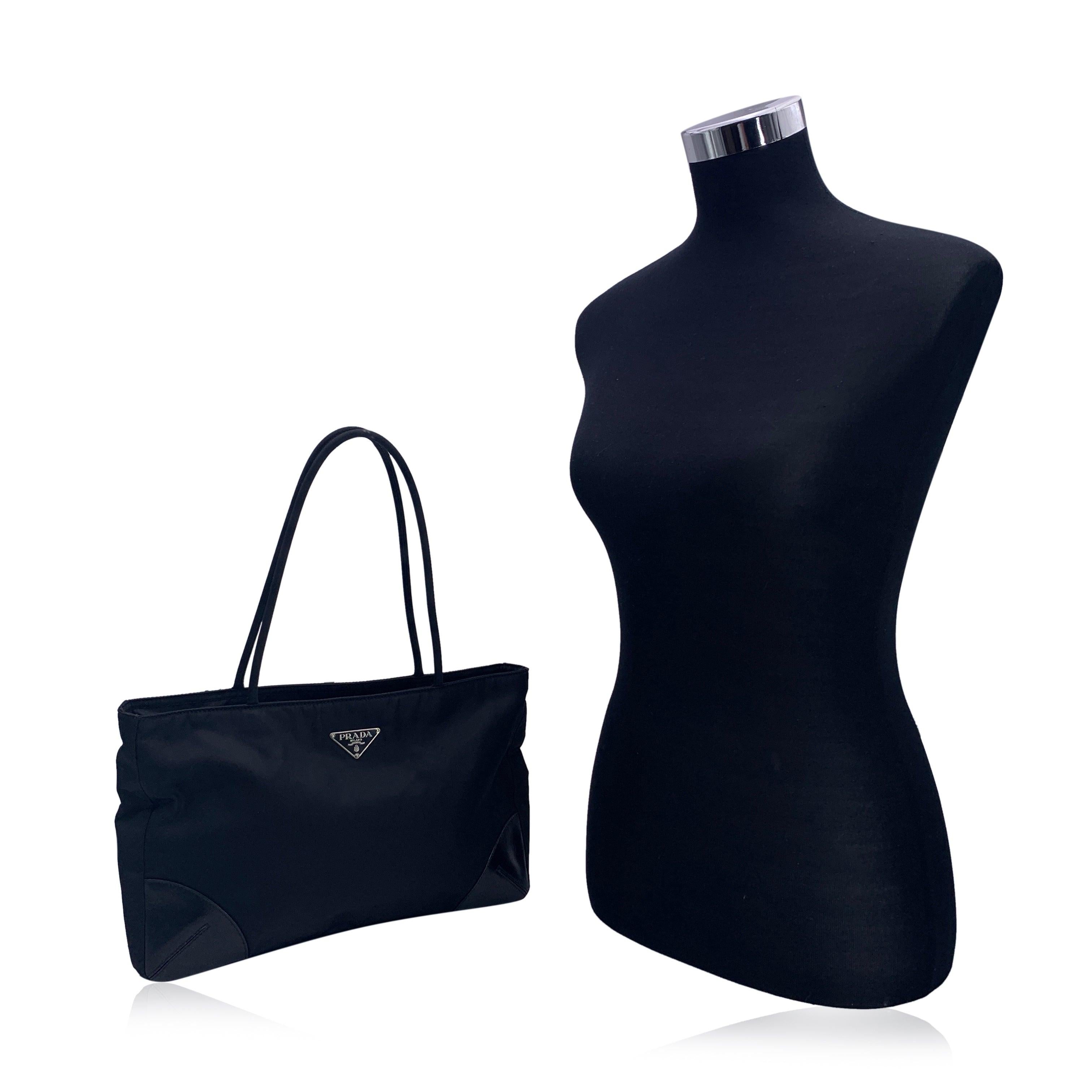 Elegant sac fourre-tout en nylon Prada Tessuto. Le sac est fabriqué en nylon noir et comporte des coins noirs. Logo triangulaire Prada sur le devant. Fermeture à glissière supérieure. Doublure noire signée. 1 poche latérale zippée à l'intérieur.