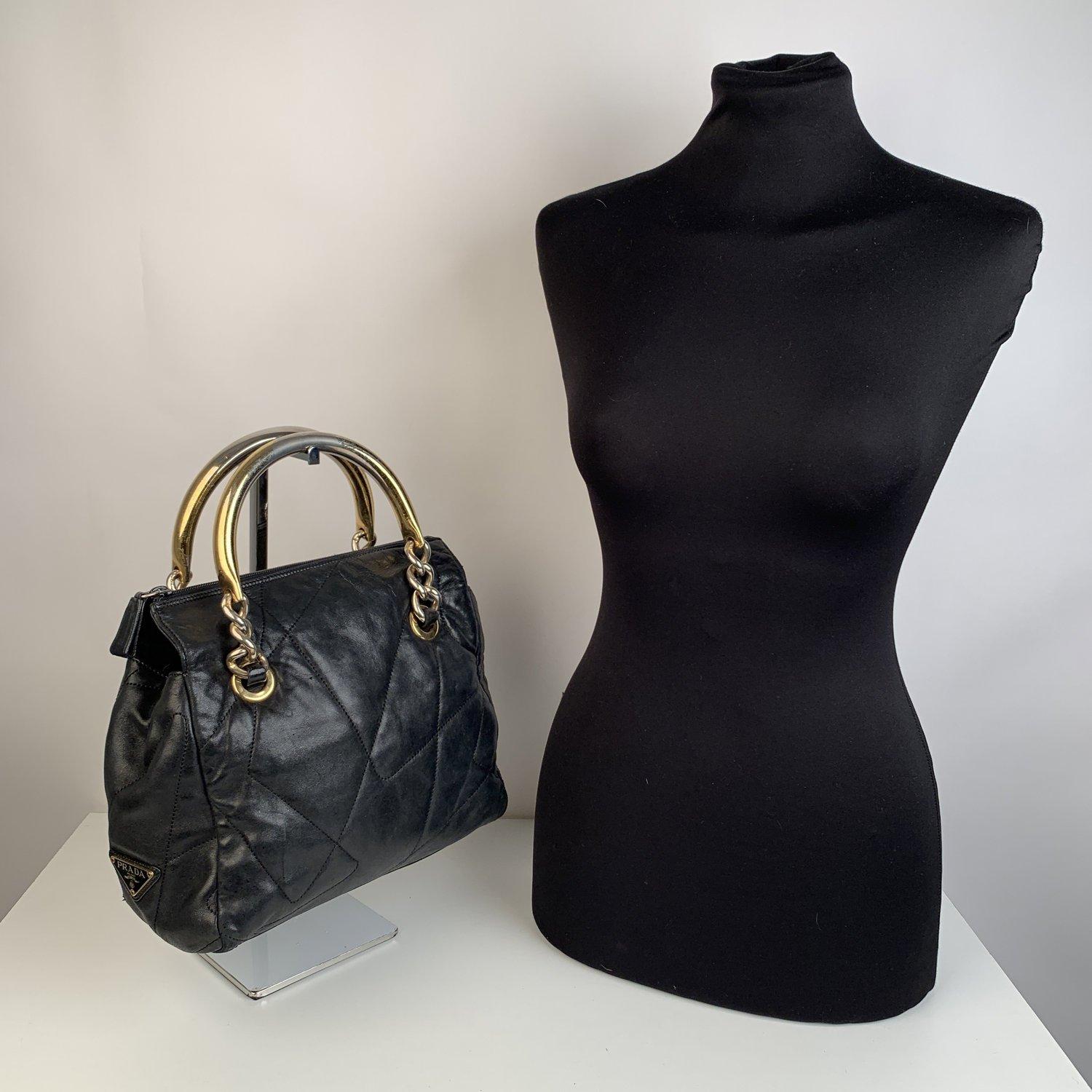 Prada Vintage black quilted leather tote bag. It features gold metal handles. Upper zipper closure. Prada signature fabric lining. 1 side zip pocket inside. Prada triangle logo plaque on the front. 'Prada Milano - Made in Italy' tag inside. Small