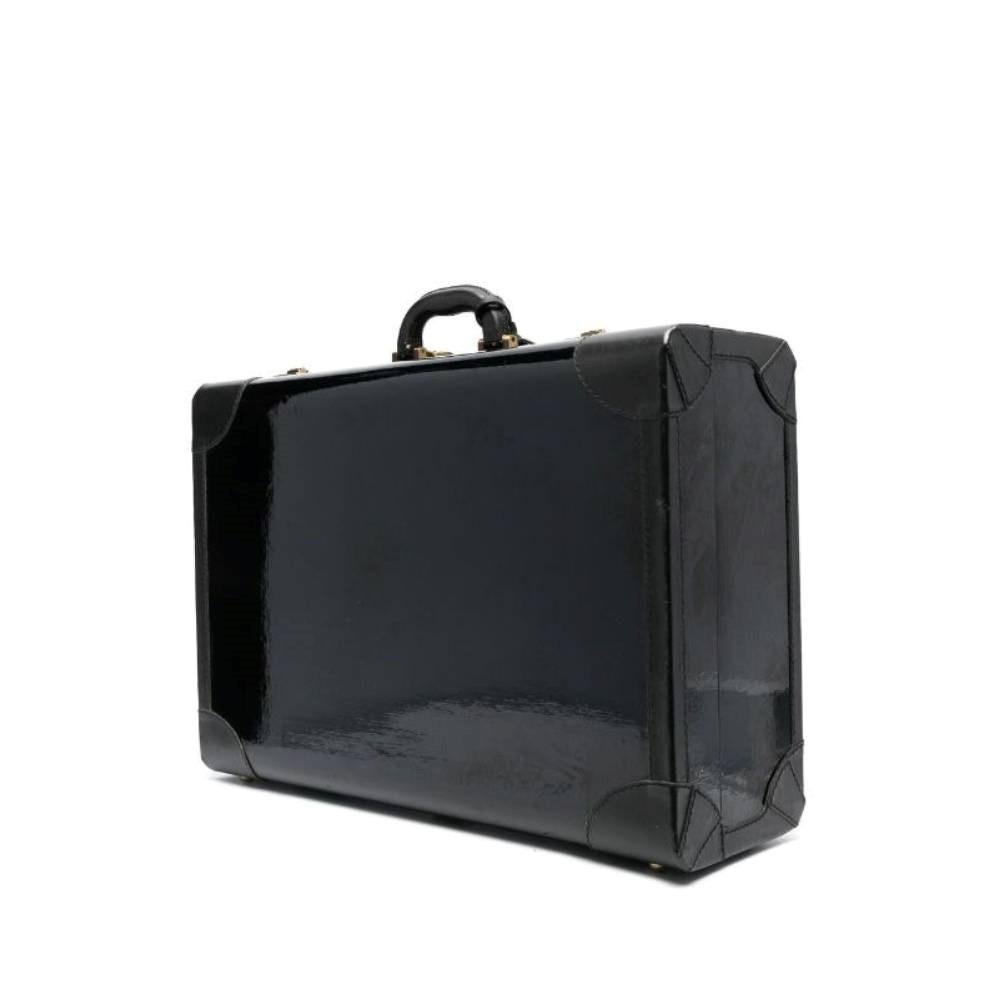 Prada black vinyl 2000s suitcase with corners covered by black leather. Handle and metal gold-tone fastening with combination lock. Two inner adjustable buckles and two patch pockets.

Height: 38 cm
Width: 60 cm
Depth: 19 cm

Product code: