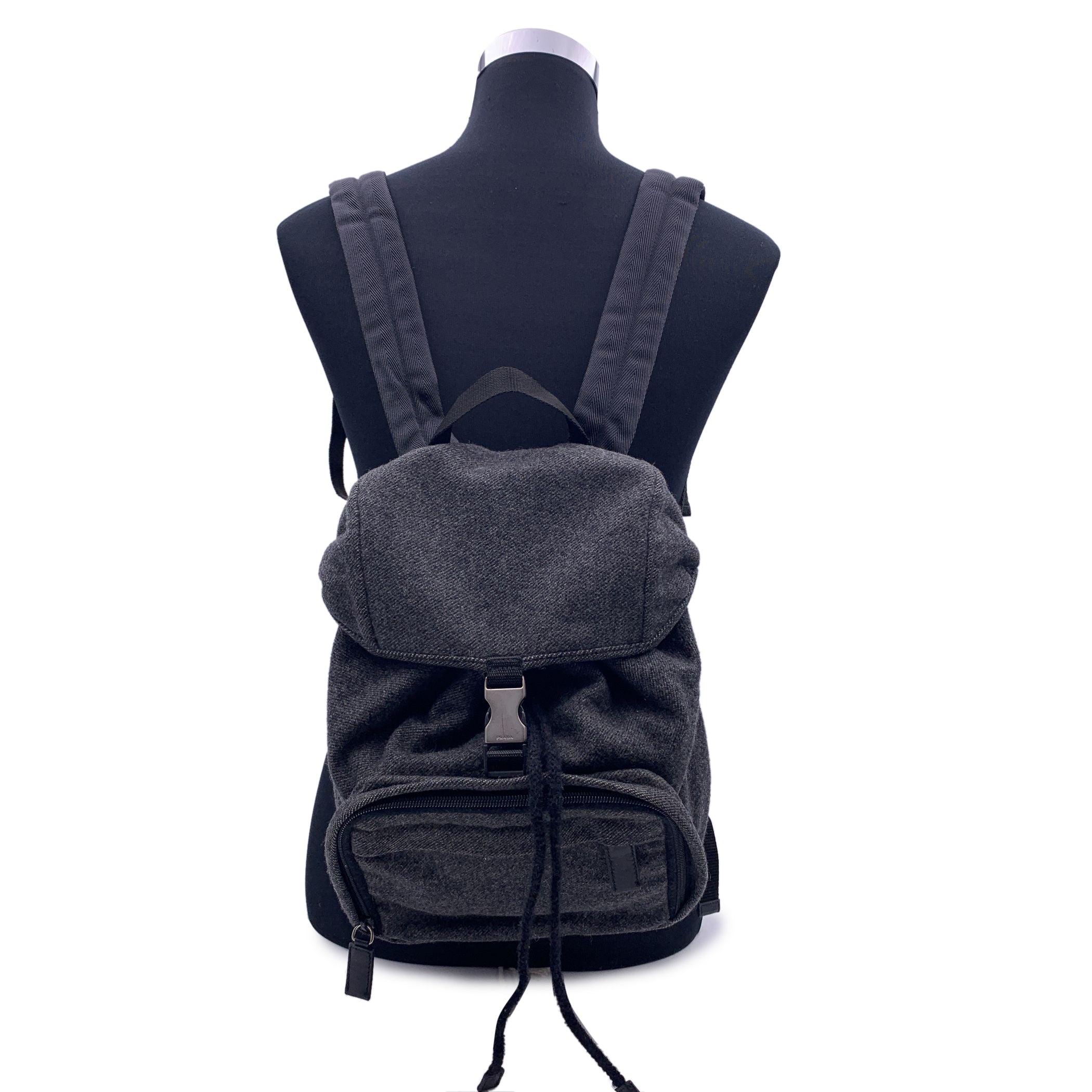 Vintage Prada grey wool Small Backpack Shoulder Bag. Front zip pocket. Front flap with single buckle closure. Drawstring on top opens to a black fabric lining. Adjustable straps. 'Prada' traingle logo on the back. 'PRADA Milano- Made in Italy' tag